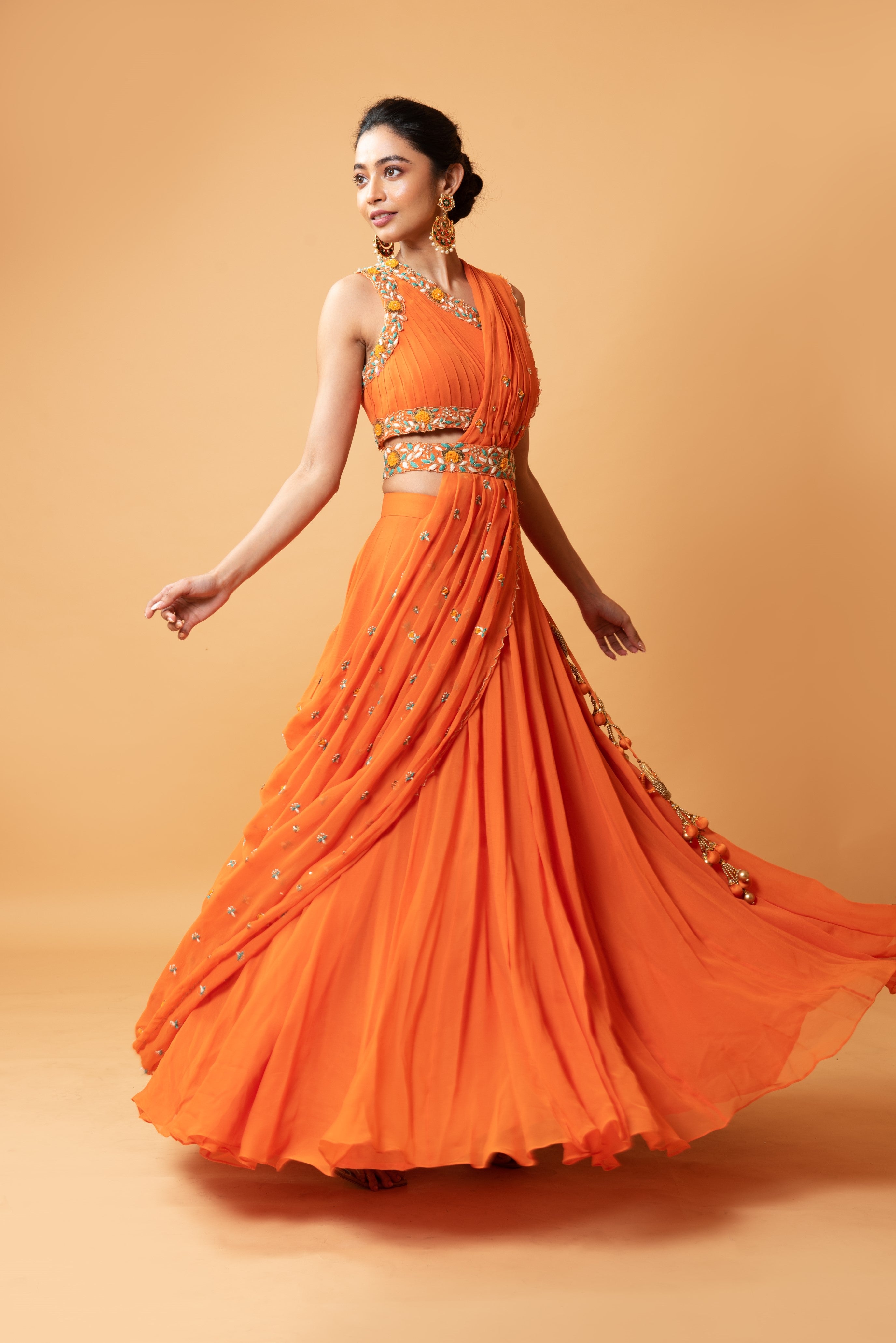 Bright orange draped lehenga with a matching embroidered belt.