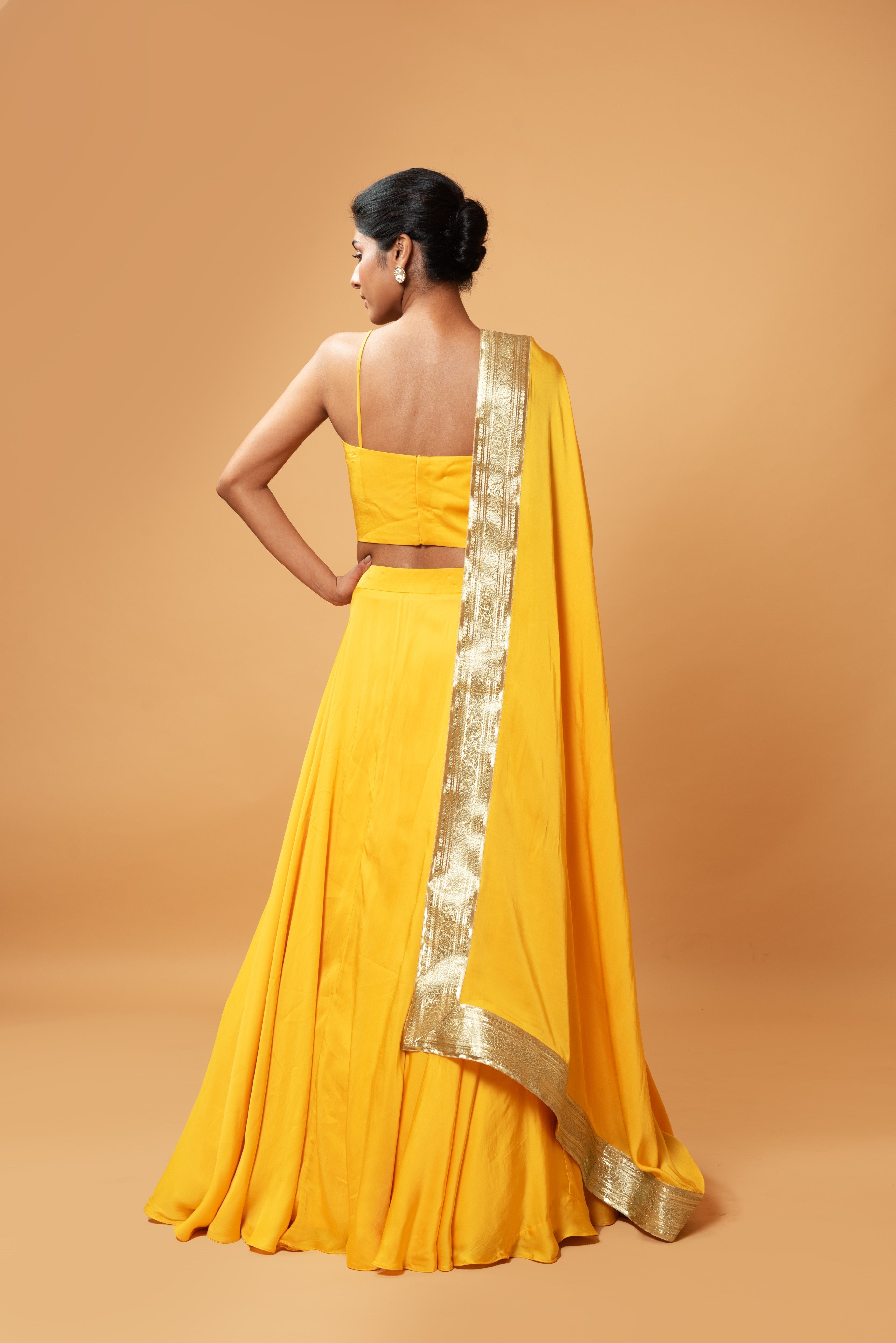 Bright yellow sleeveless lehenga with golden zari-bordered dupatta.