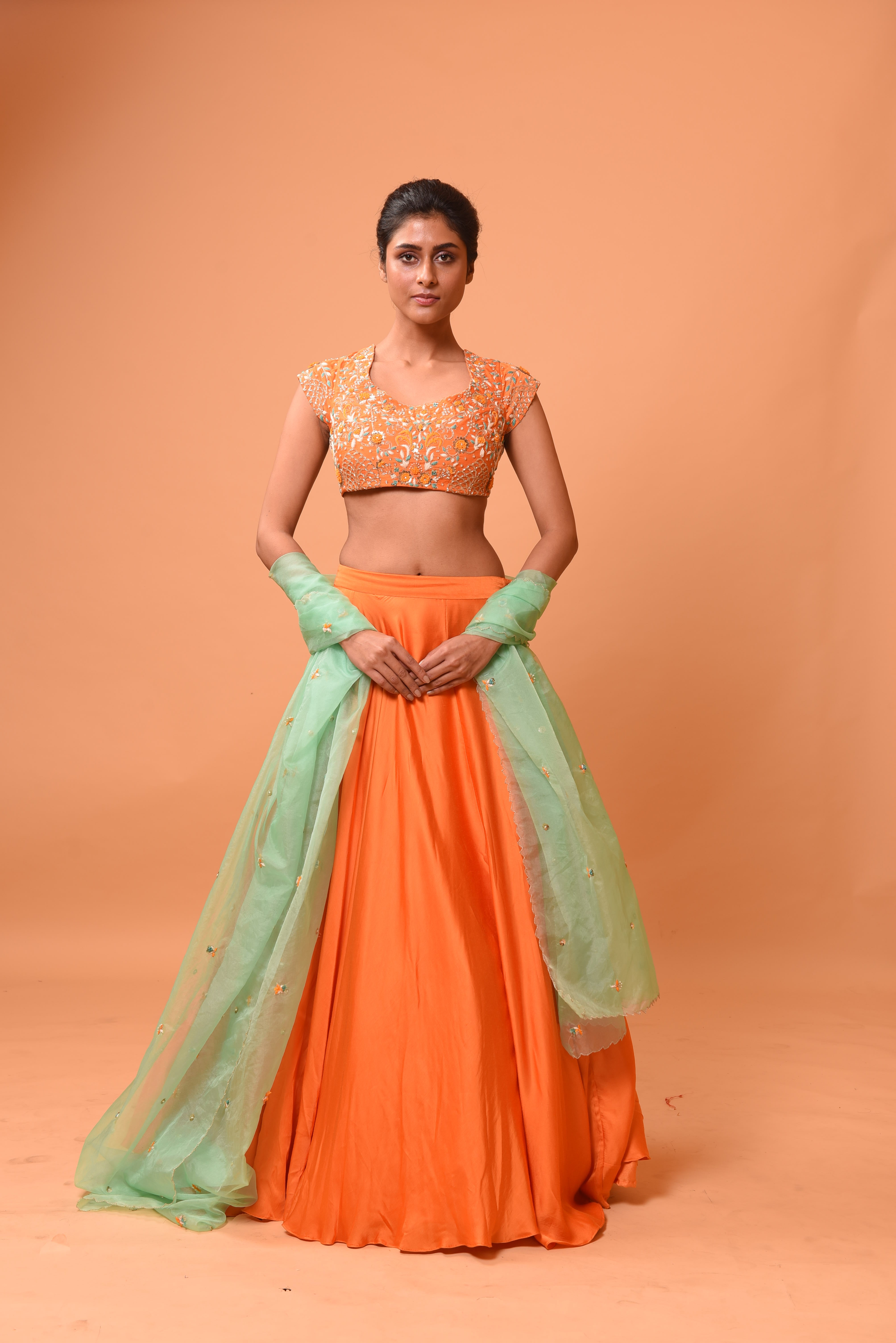 Bright orange lehenga with turquoise dupatta and intricate handwork.