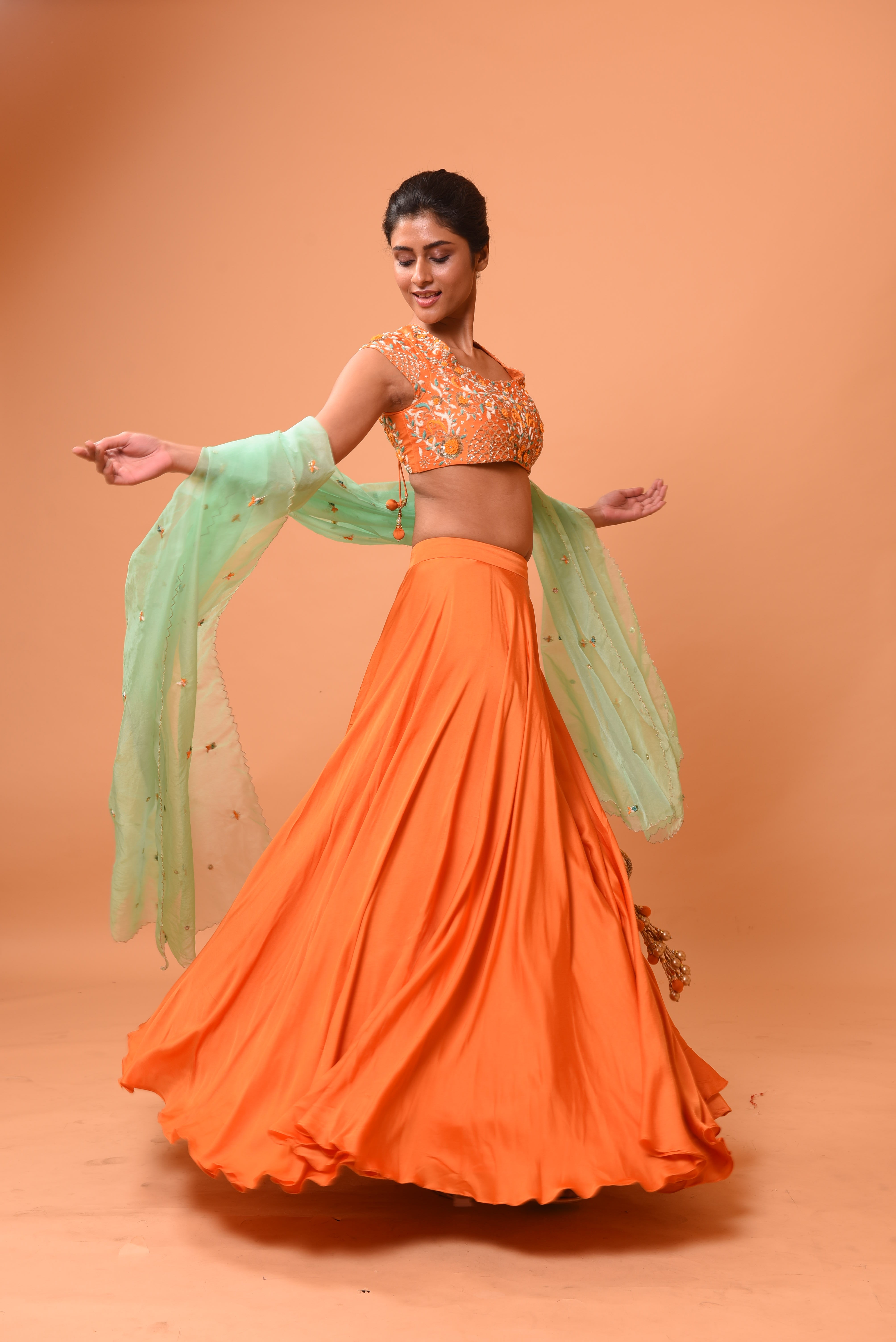 Bright orange lehenga with turquoise dupatta and intricate handwork.