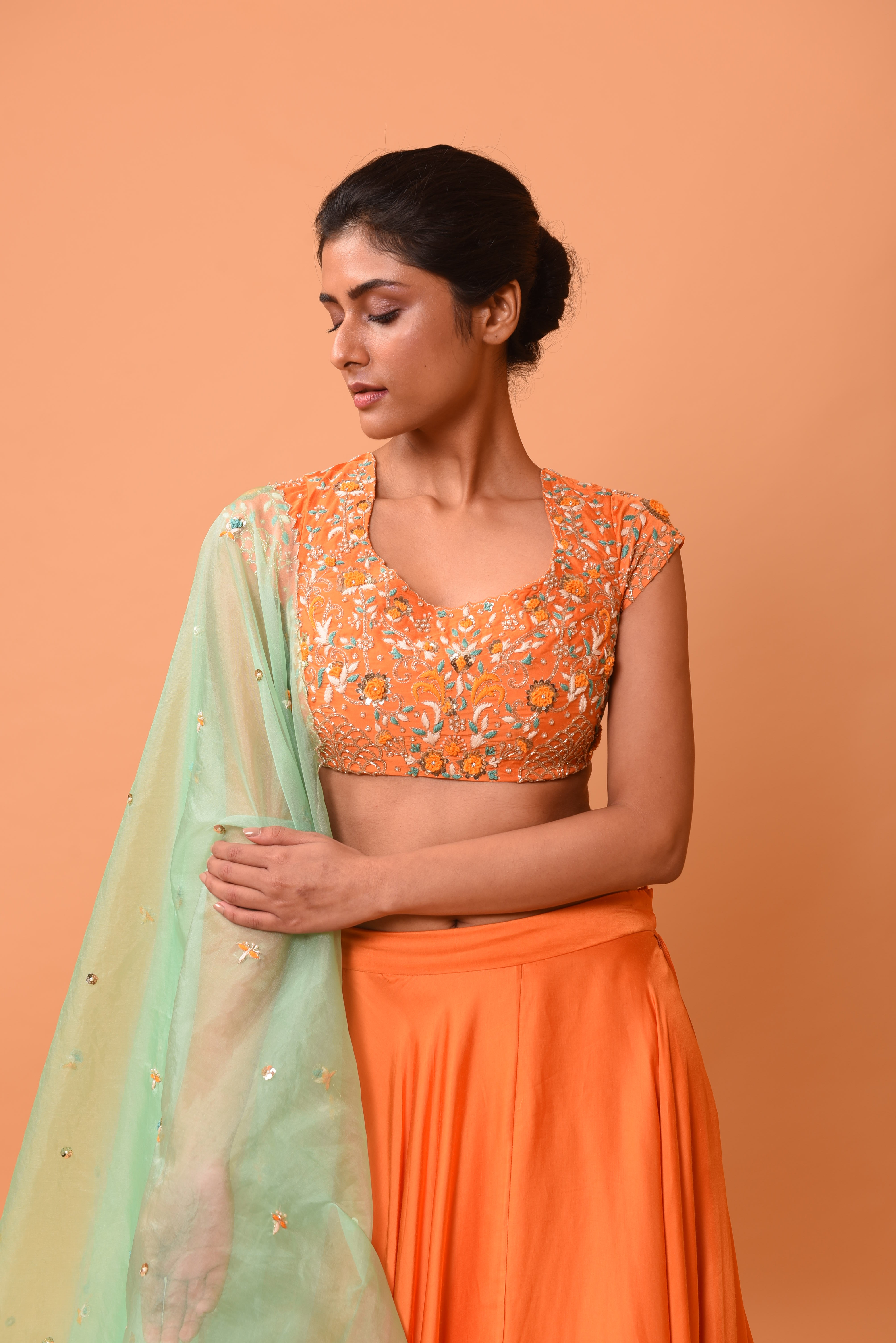 Bright orange lehenga with turquoise dupatta and intricate handwork.