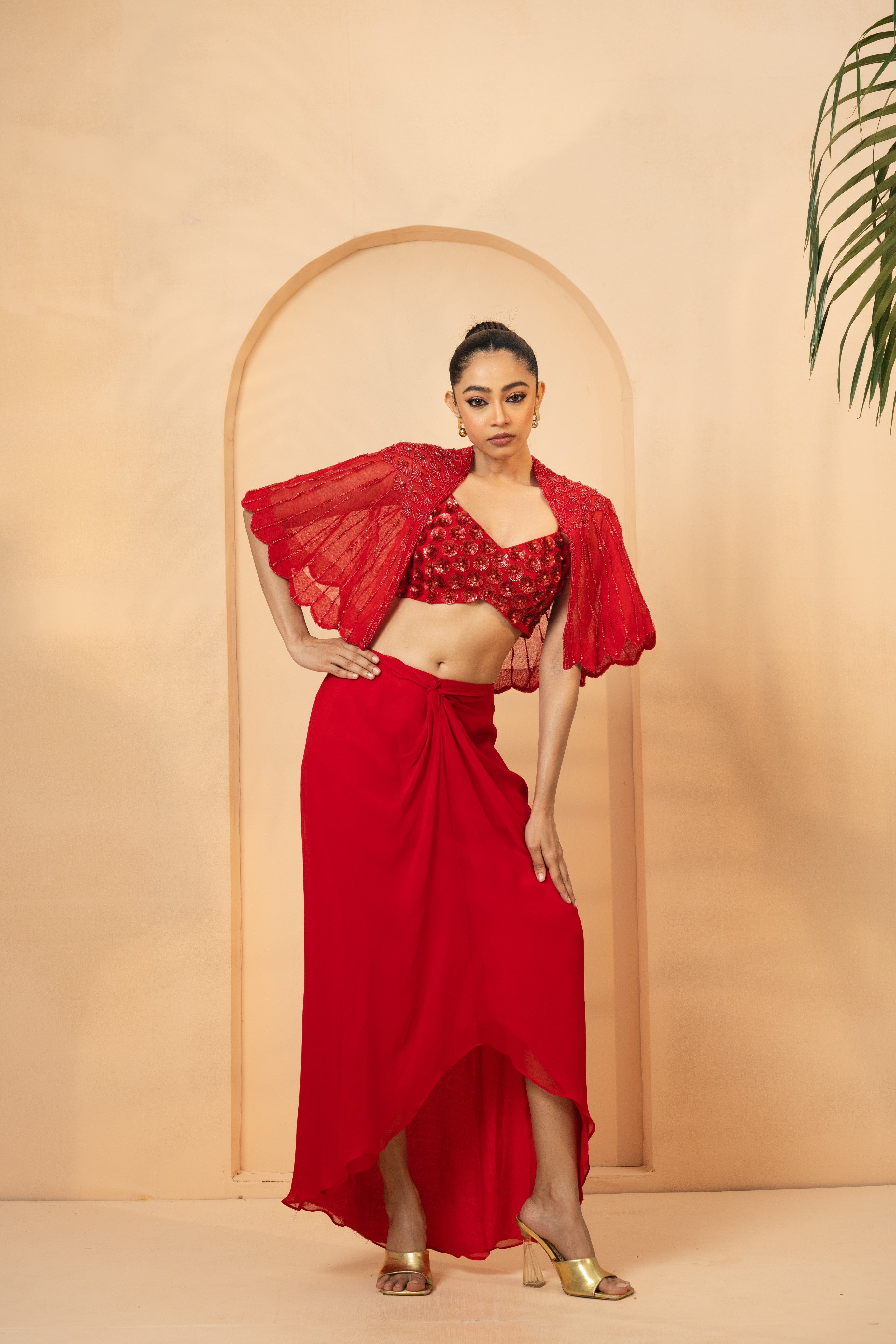 Red co-ord set with hand-embroidered blouse, cape, and dhoti skirt.