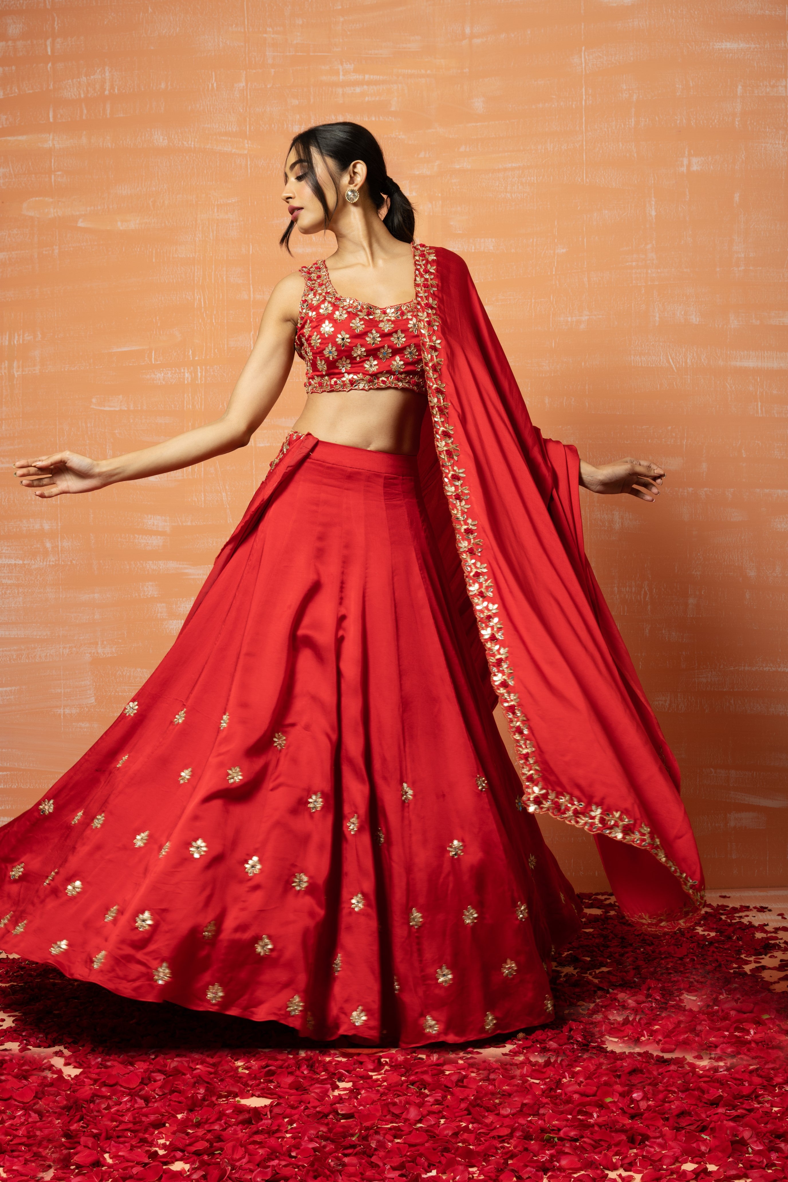 Red hand-embroidered lehenga in modal silk with intricate detailing.