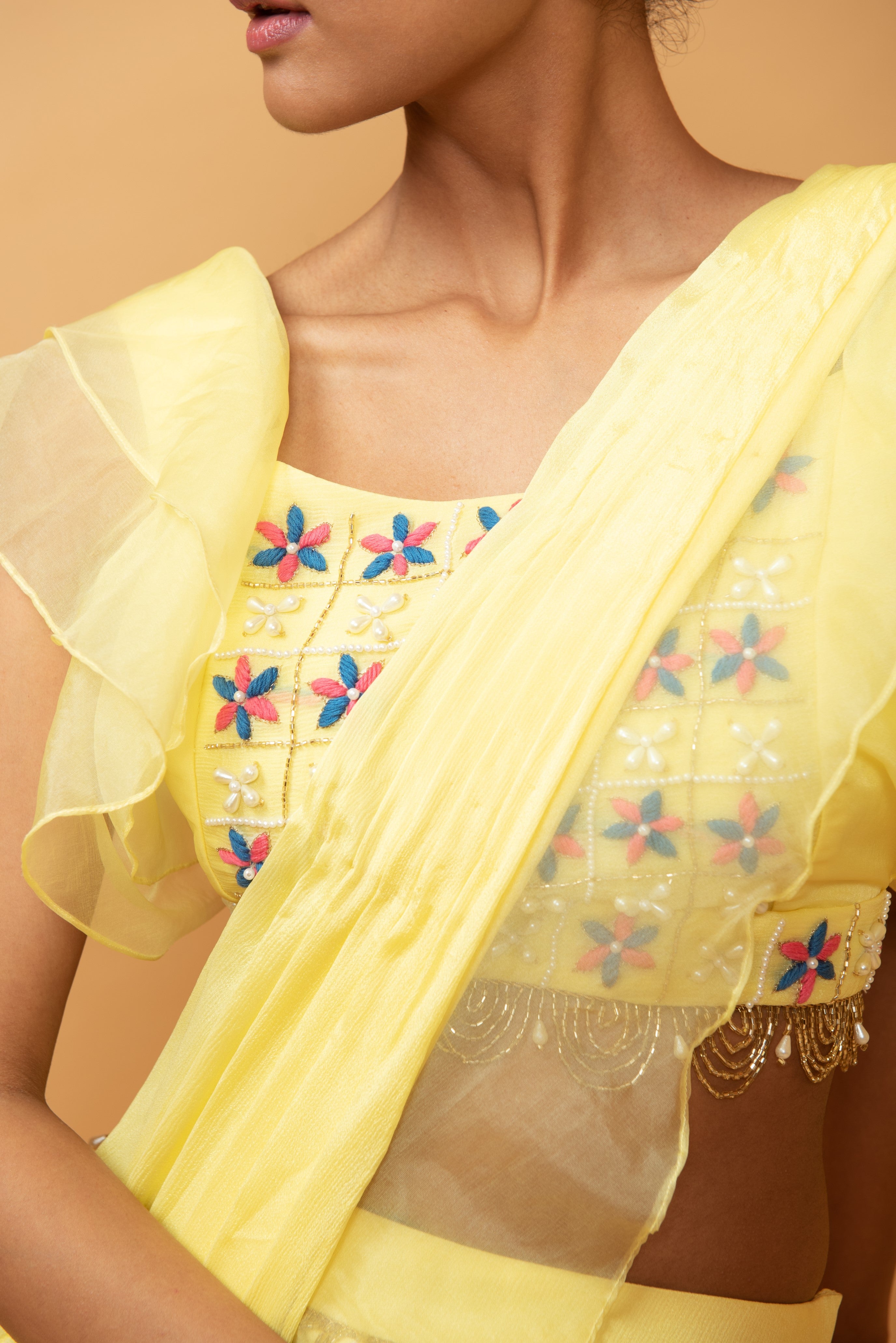 Yellow ruffle saree with lace work and embroidered blouse featuring intricate handwork.