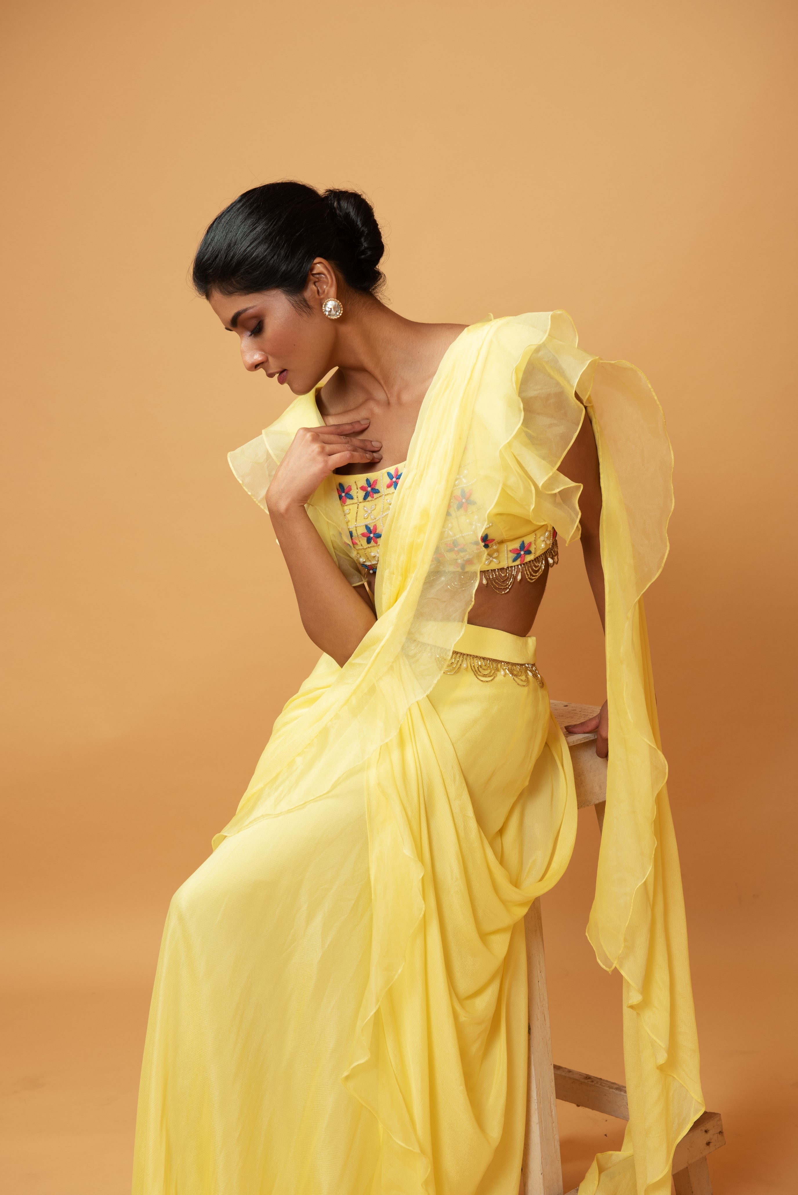 Yellow ruffle saree with lace work and embroidered blouse featuring intricate handwork.