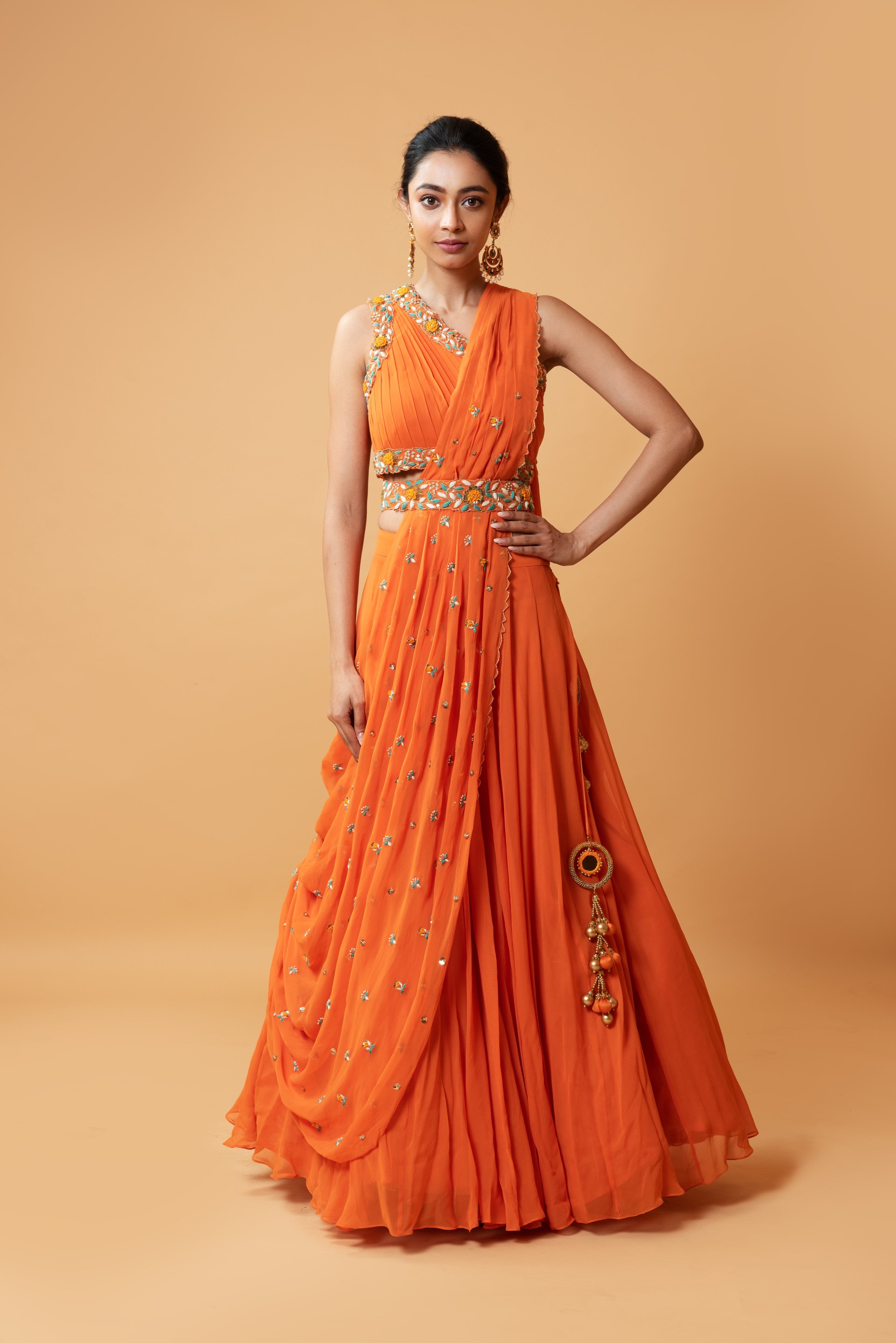 Bright orange draped lehenga with a matching embroidered belt.