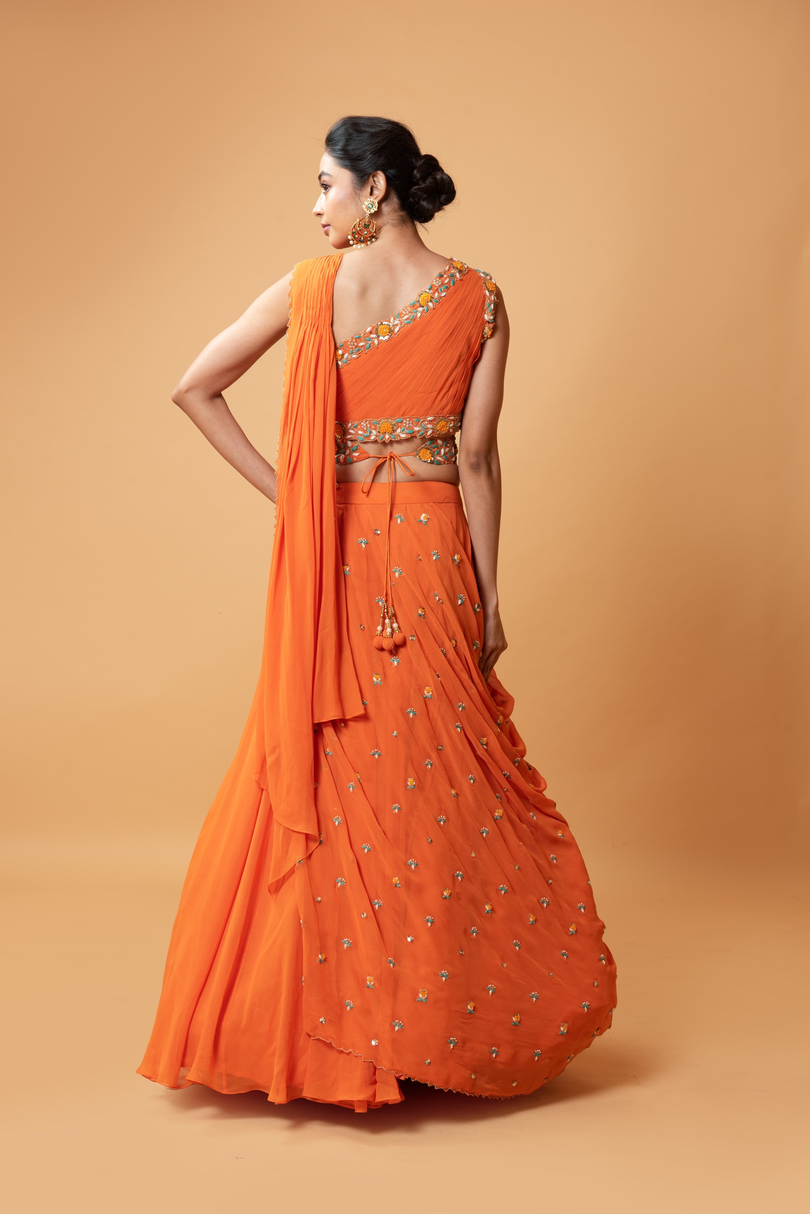 Bright orange draped lehenga with a matching embroidered belt.