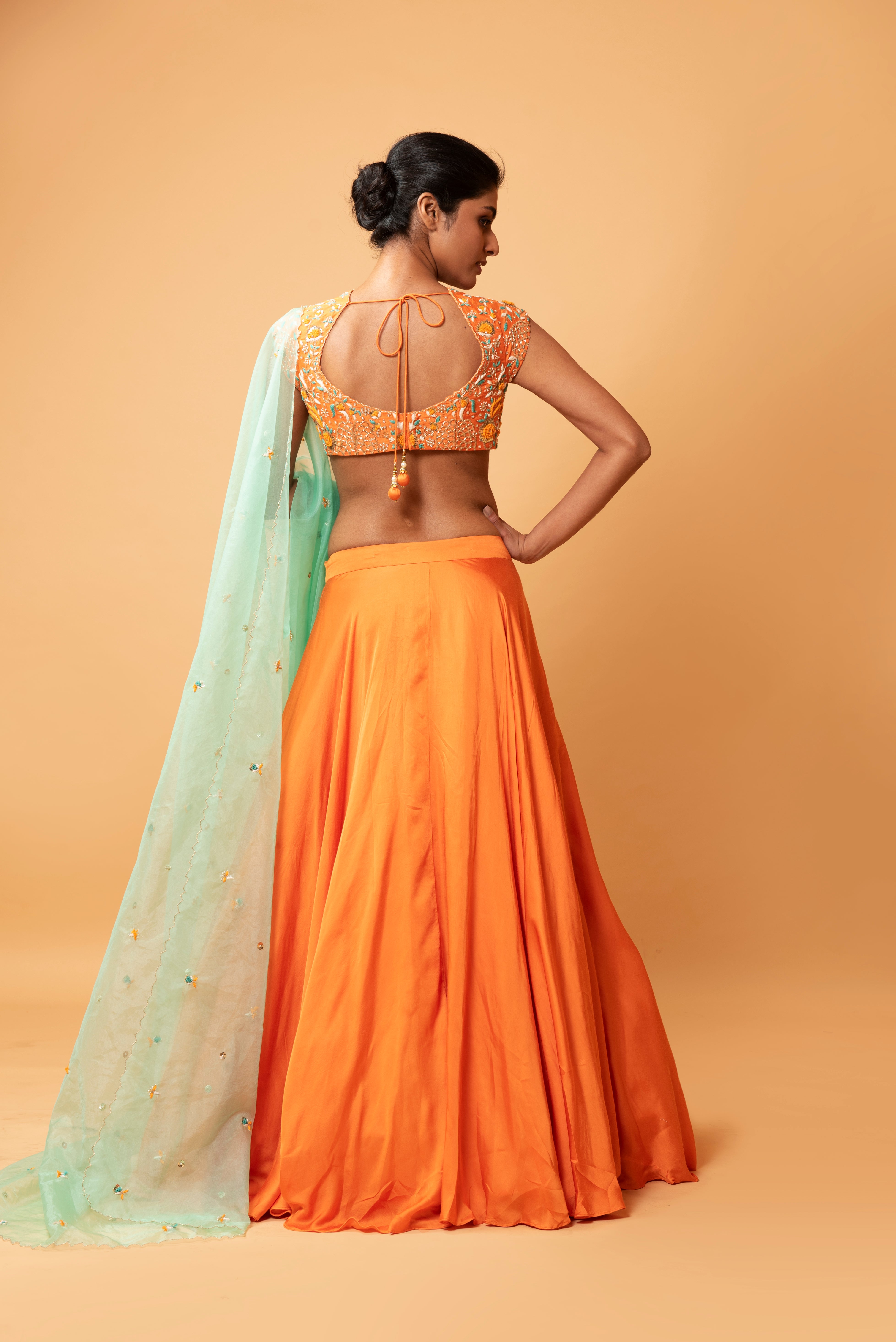 Bright orange lehenga with turquoise dupatta and intricate handwork.