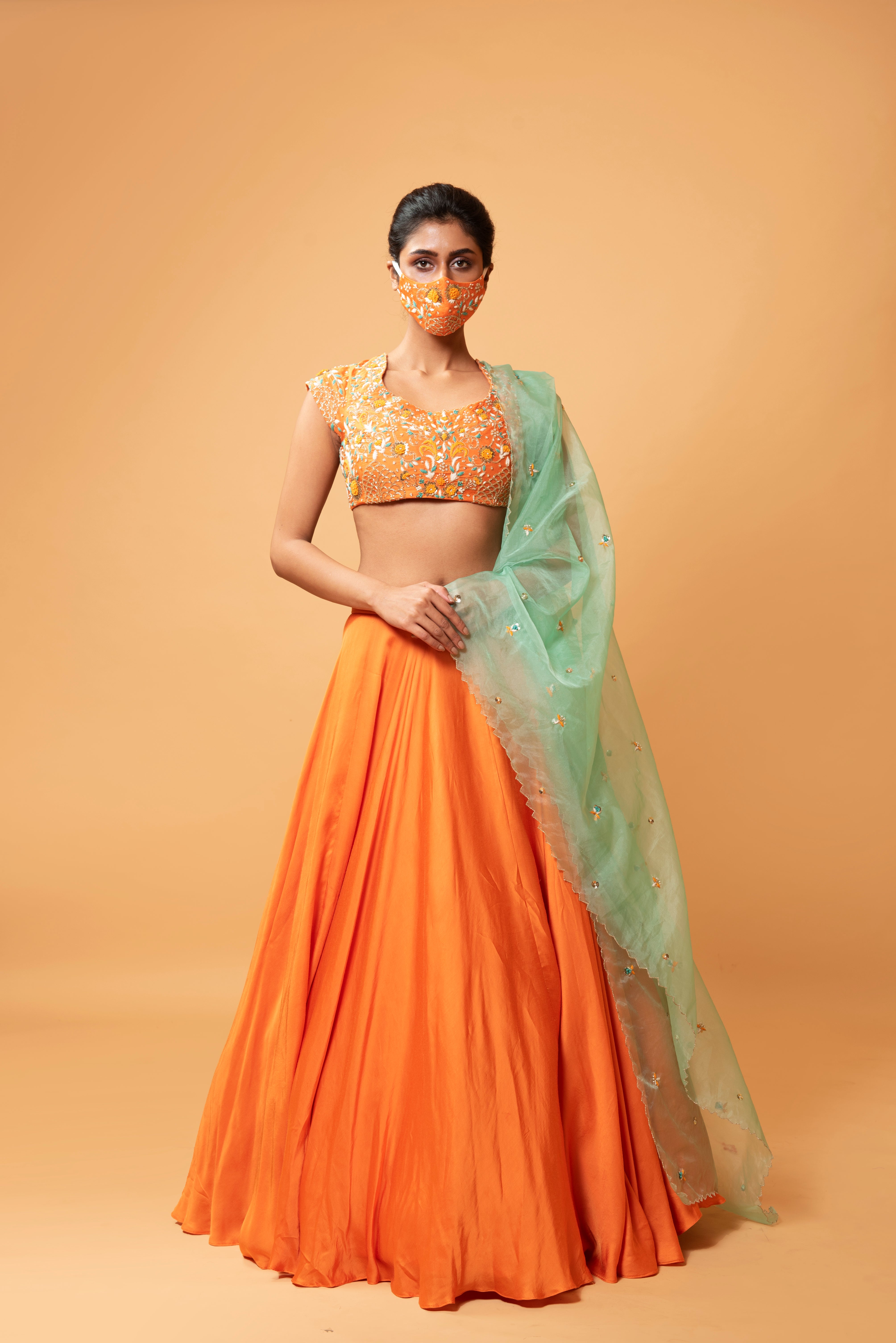 Bright orange lehenga with turquoise dupatta and intricate handwork.