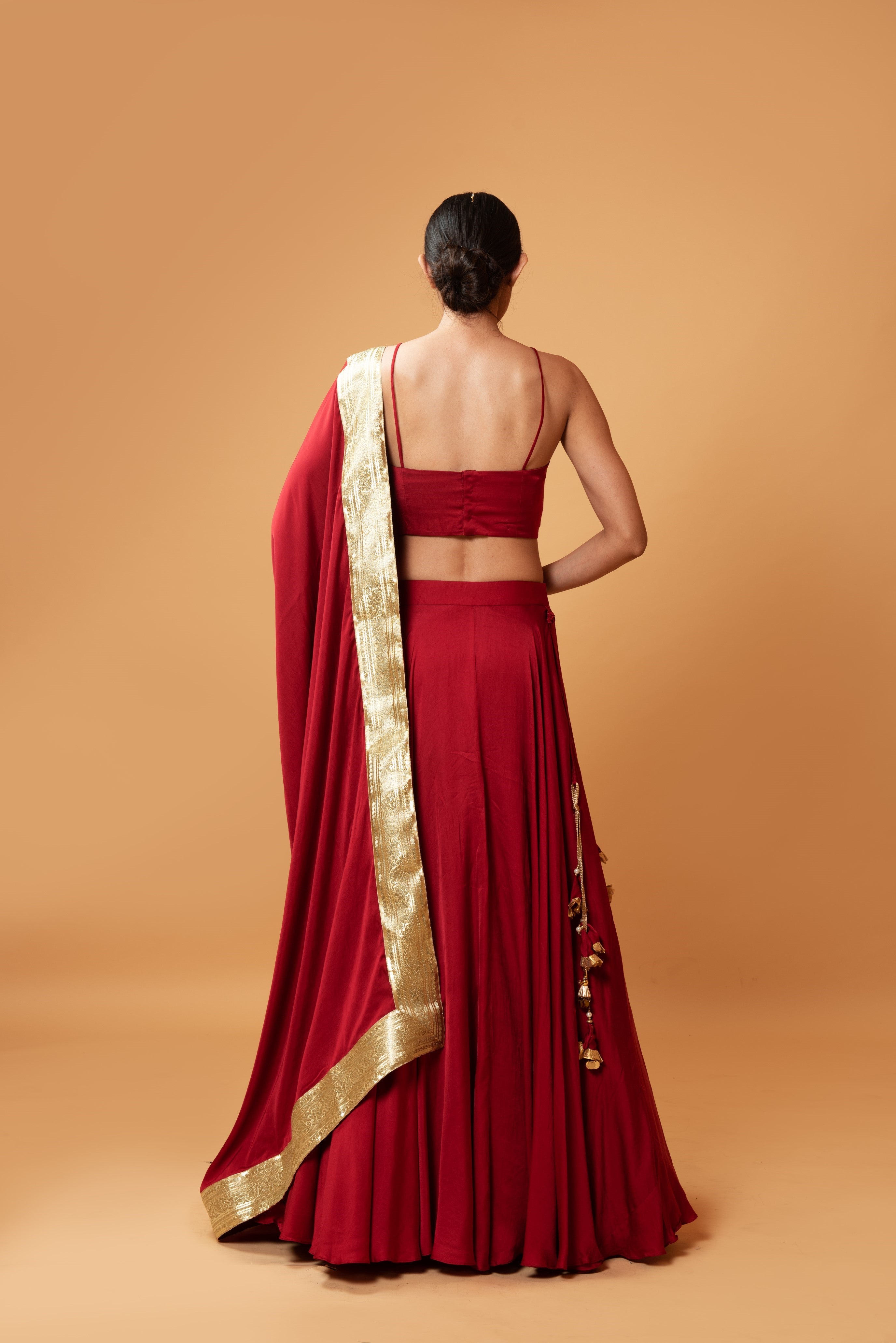 Deep red sleeveless lehenga with golden zari-bordered dupatta.