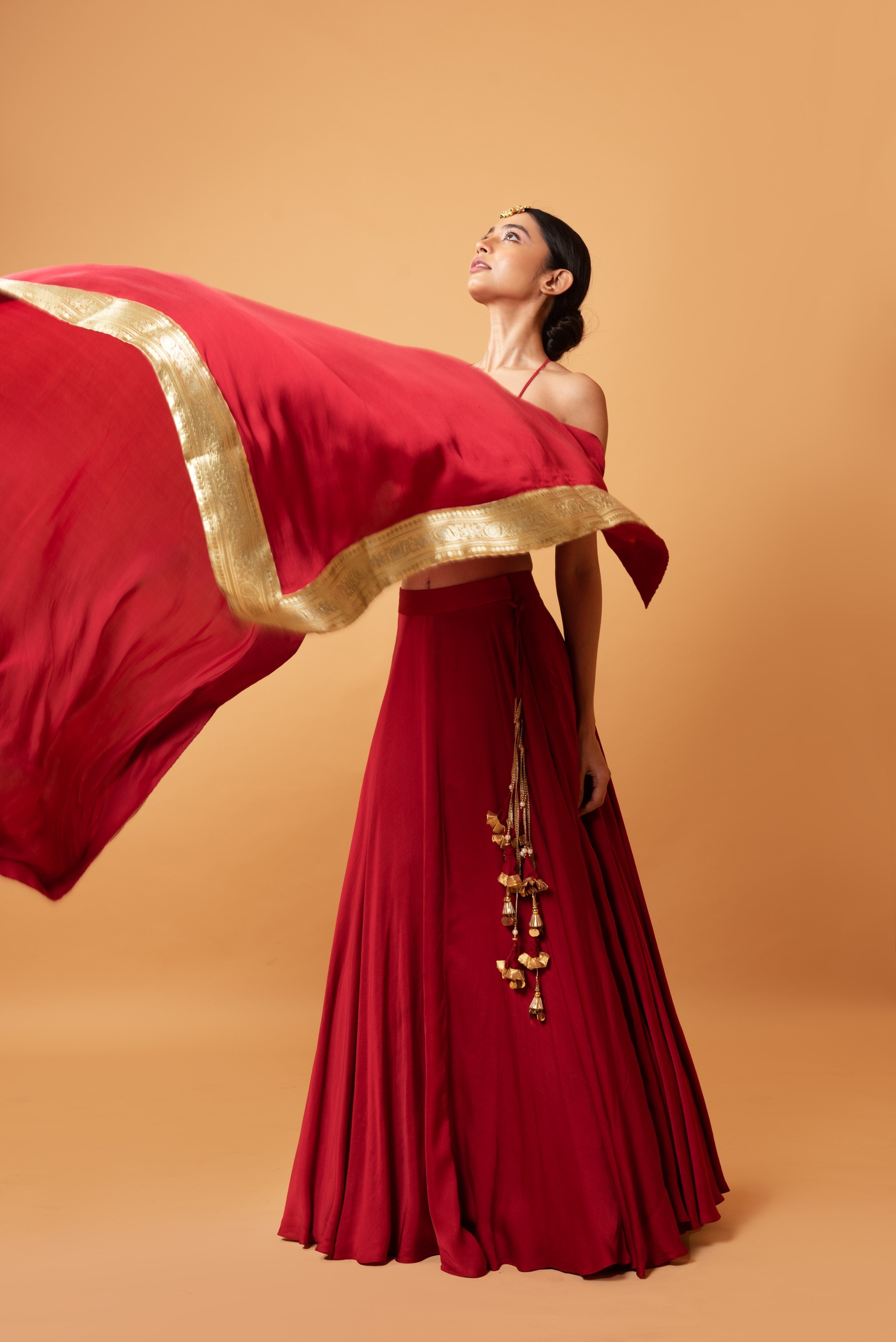 Deep red sleeveless lehenga with golden zari-bordered dupatta.