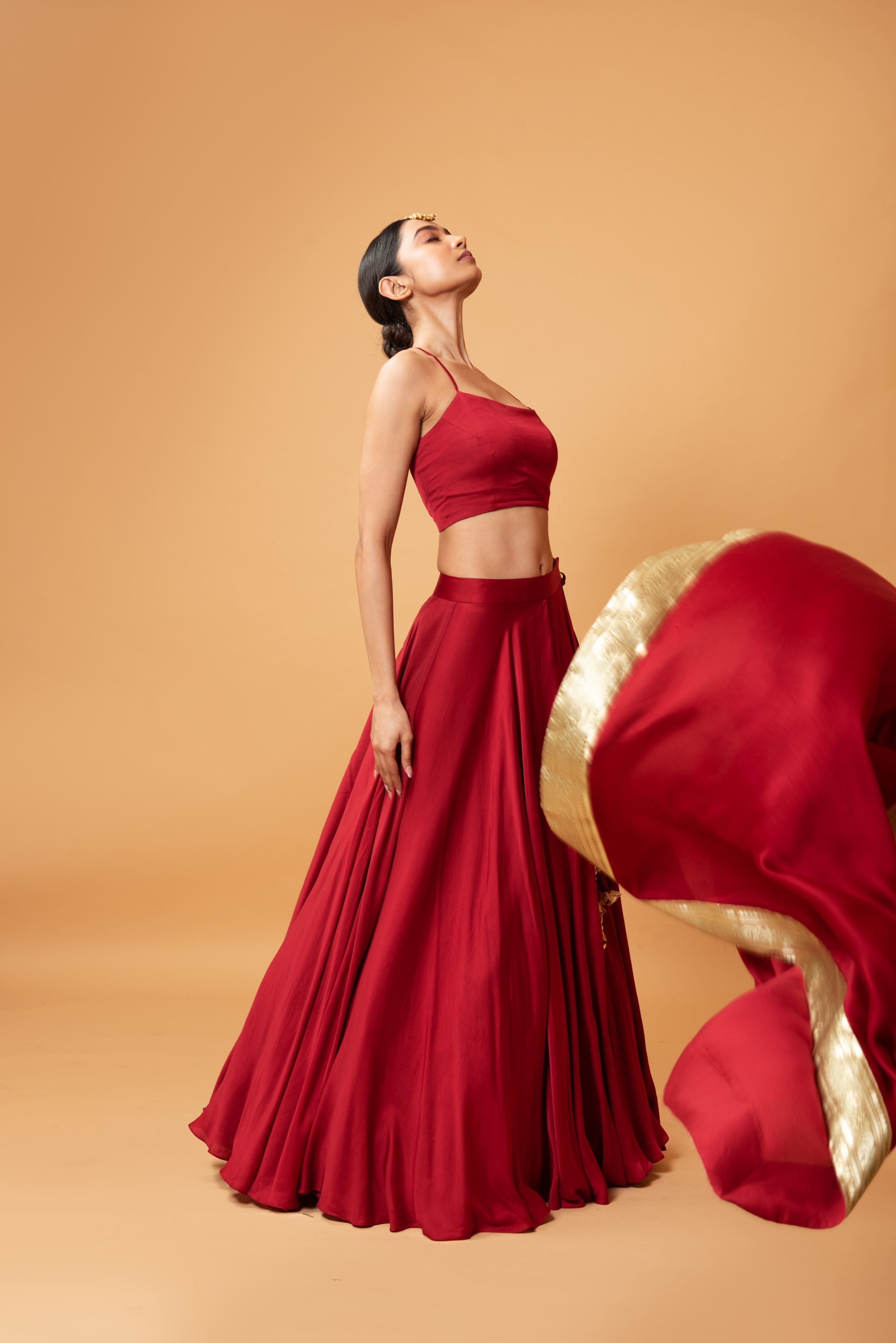 Deep red sleeveless lehenga with golden zari-bordered dupatta.