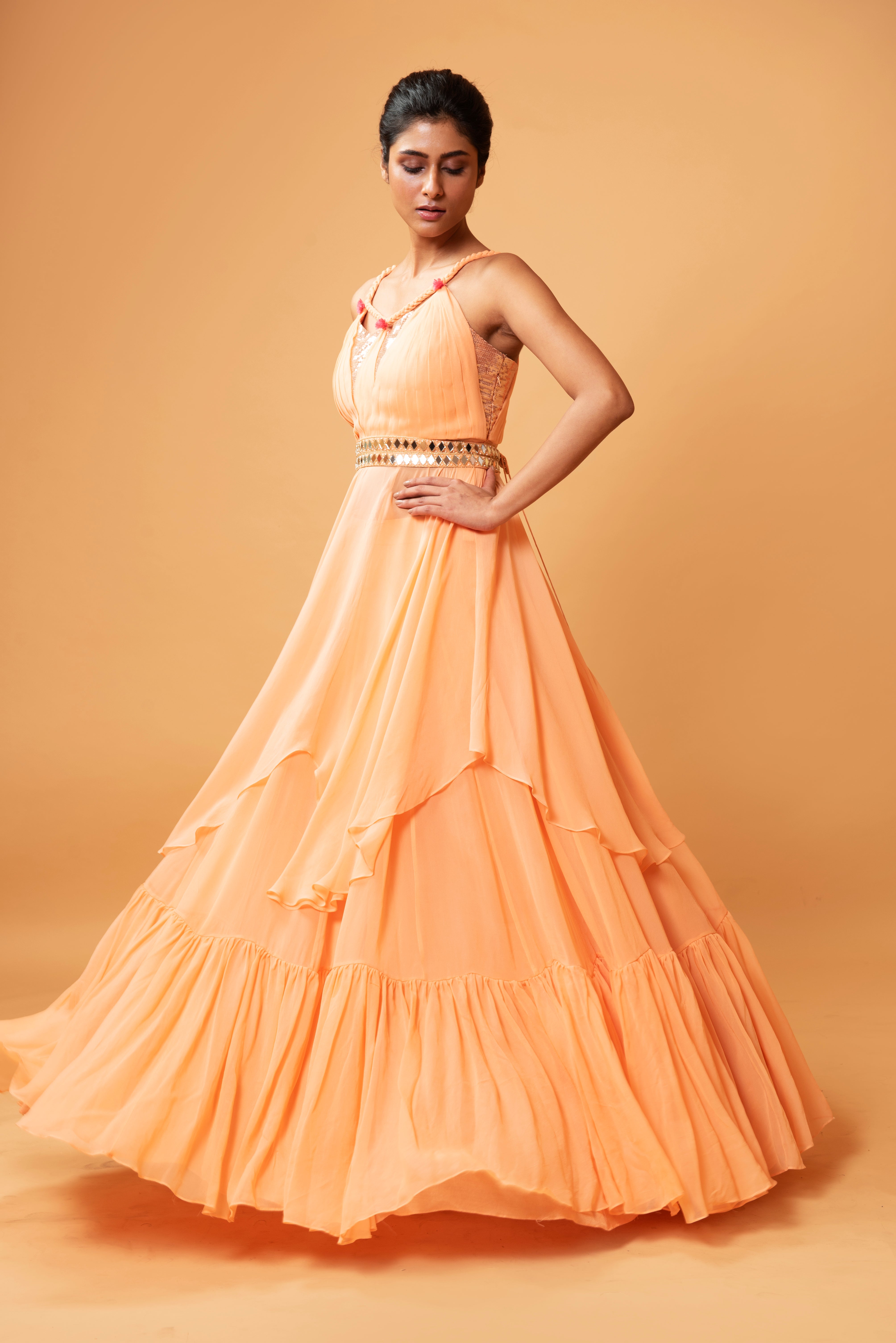 Peach sleeveless co-ord set with sequins, ruffled lehenga, and mirror-embellished waist belt.