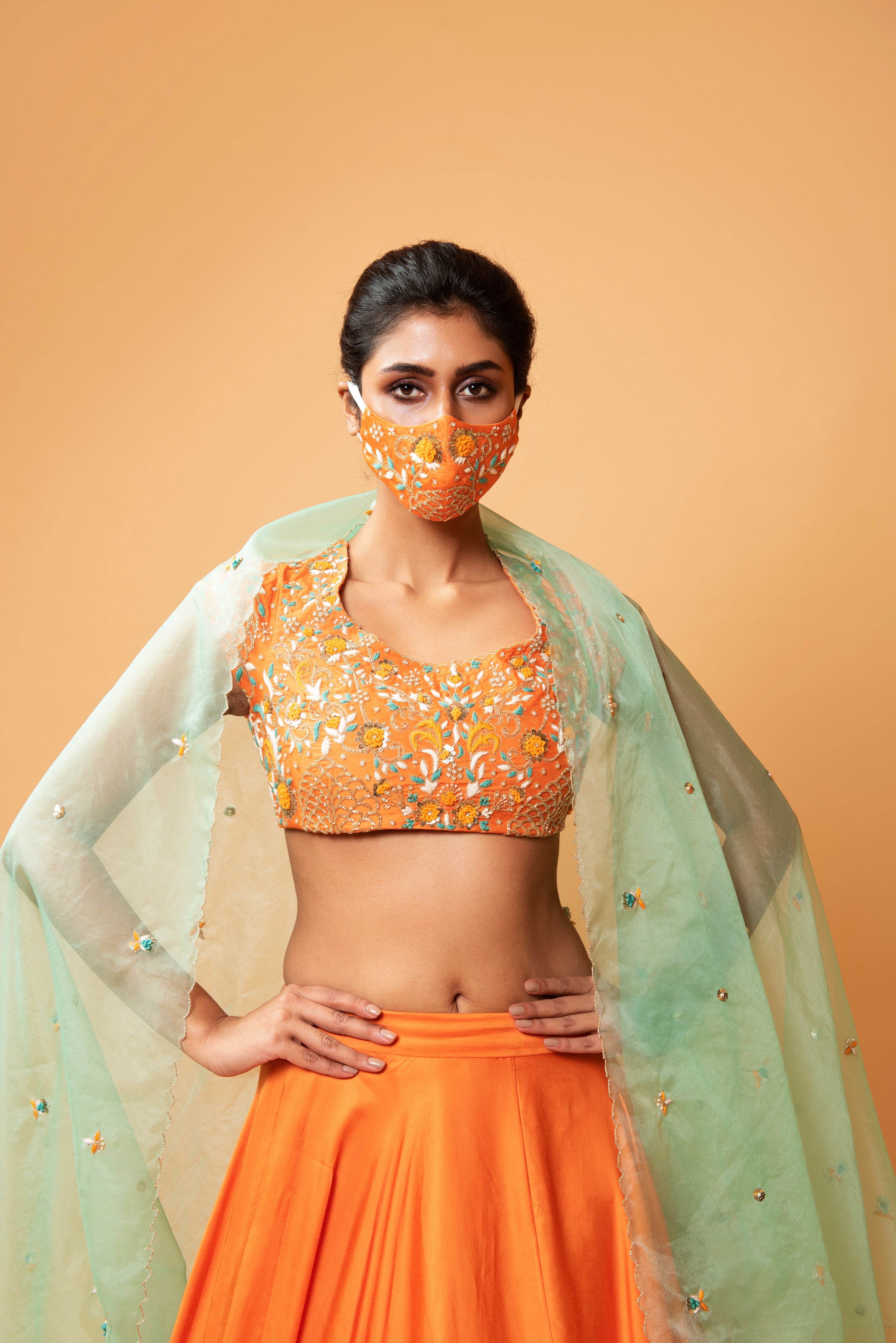 Bright orange lehenga with turquoise dupatta and intricate handwork.