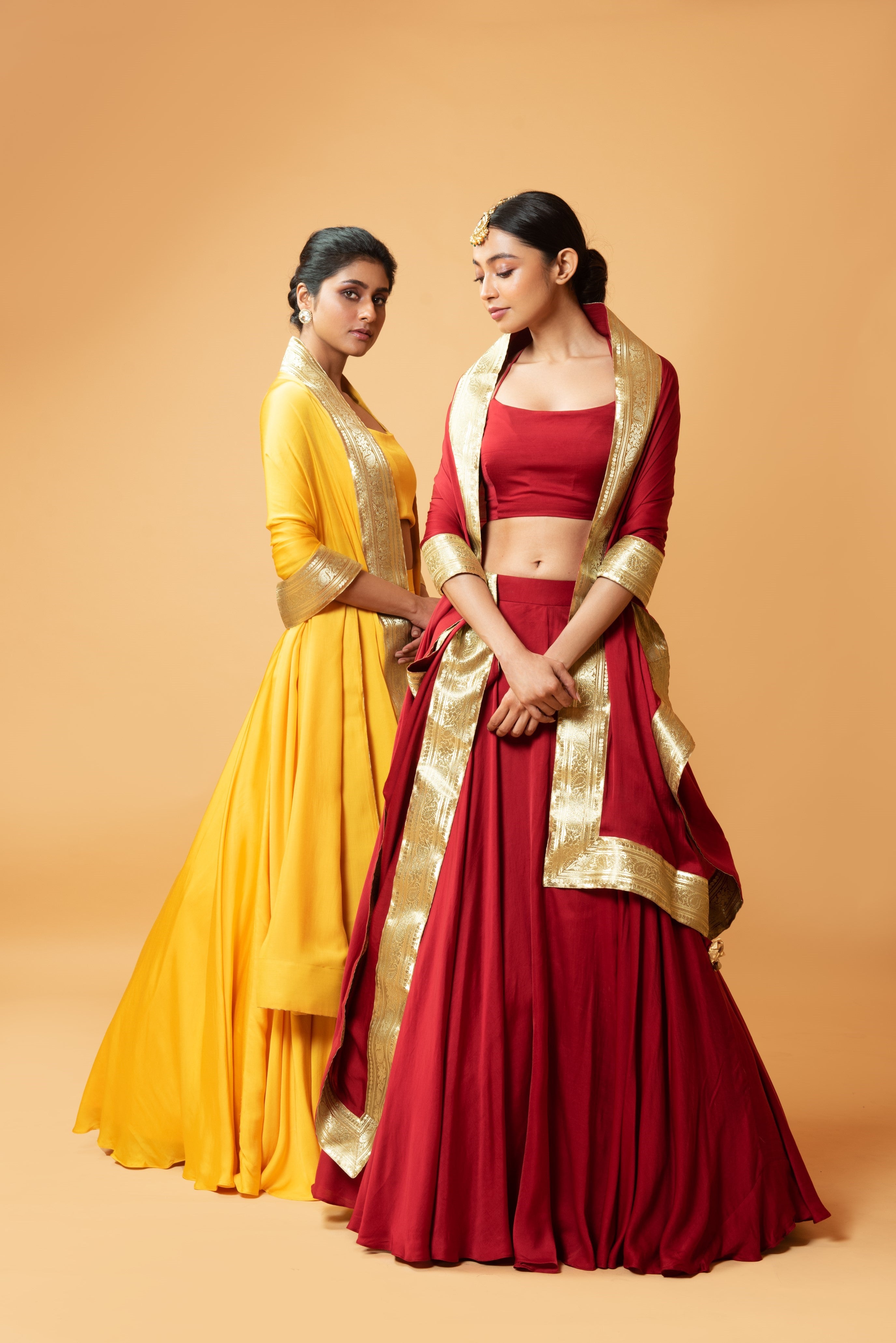 Deep red sleeveless lehenga with golden zari-bordered dupatta.