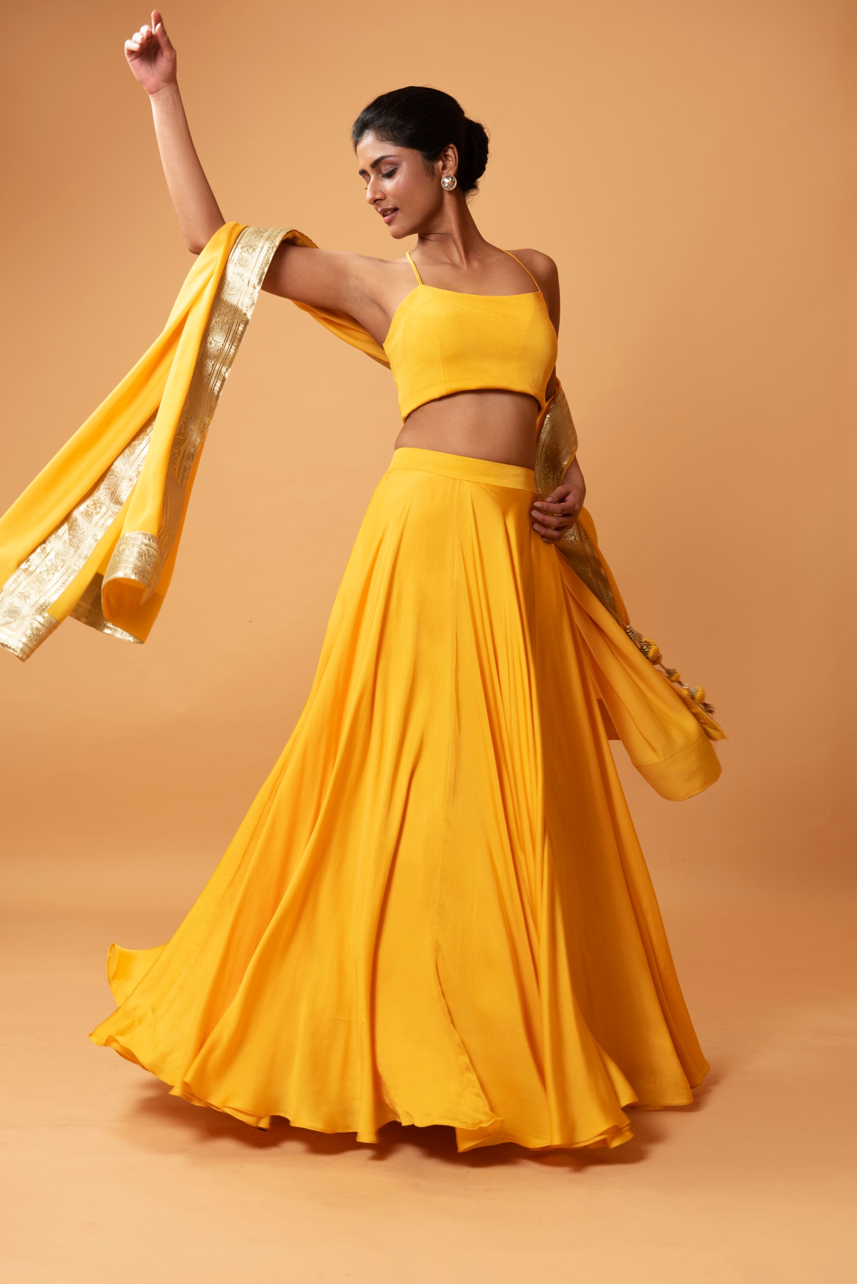 Bright yellow sleeveless lehenga with golden zari-bordered dupatta.