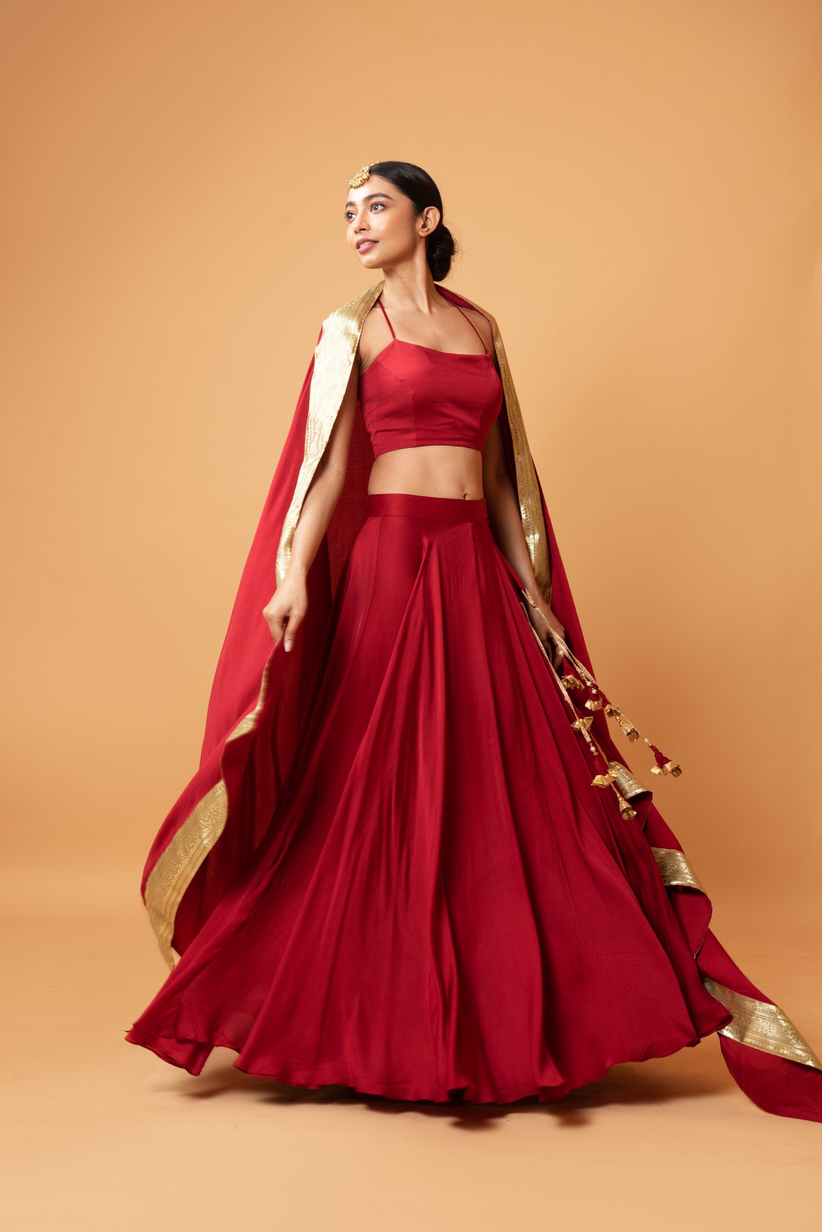Deep red sleeveless lehenga with golden zari-bordered dupatta.