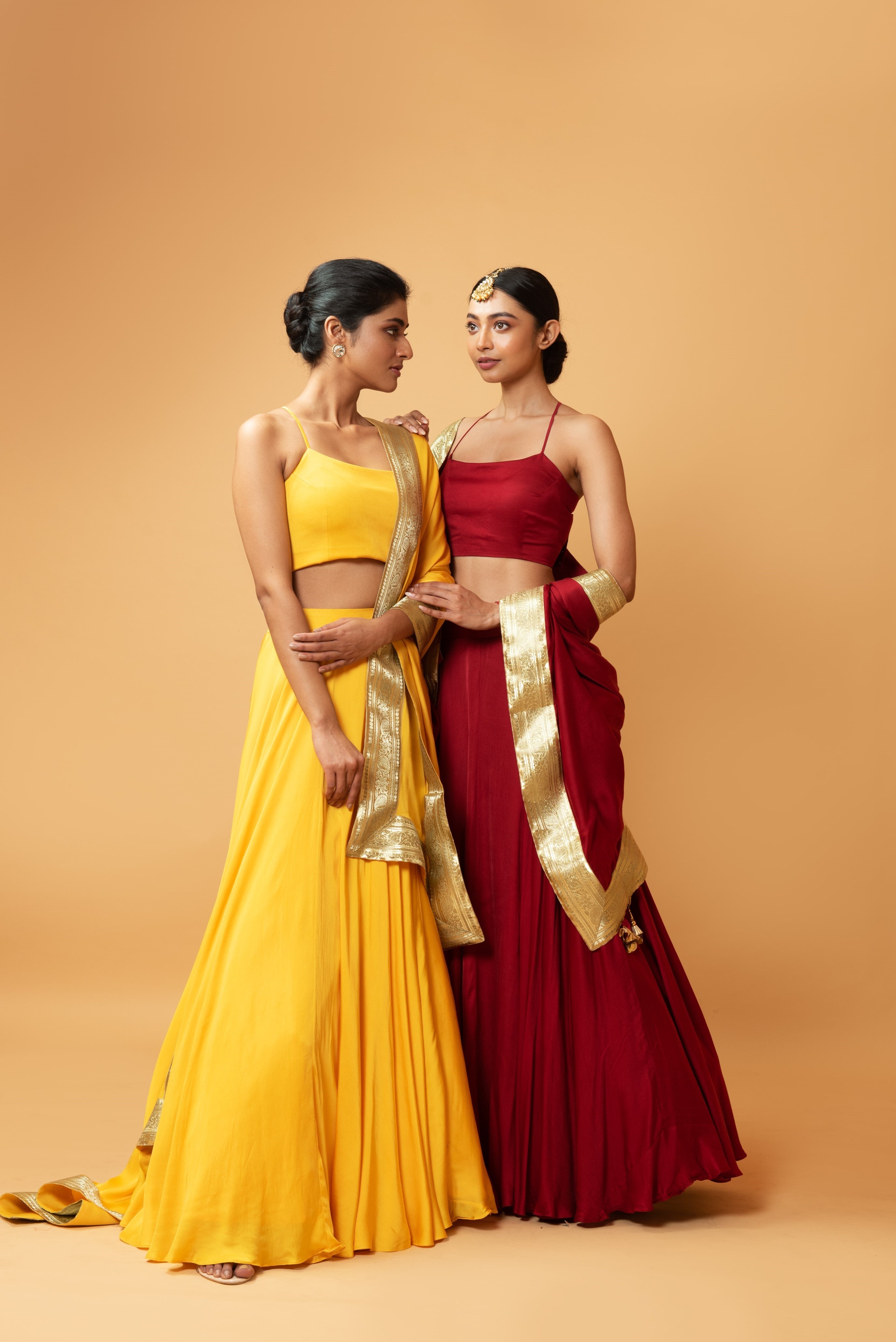 Deep red sleeveless lehenga with golden zari-bordered dupatta.