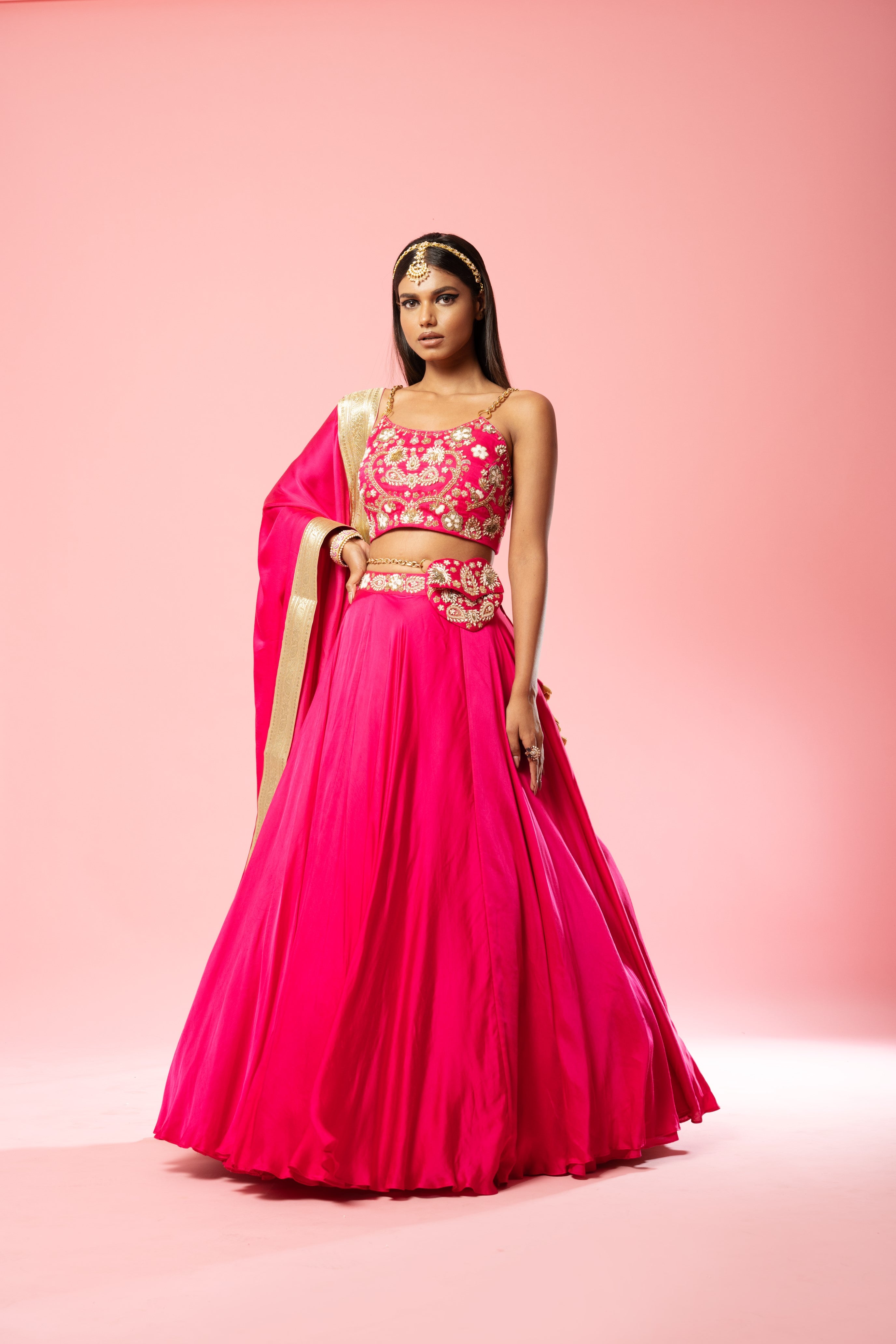 Hot pink lehenga with hand embroidery, lace dupatta, and metal sleeves.