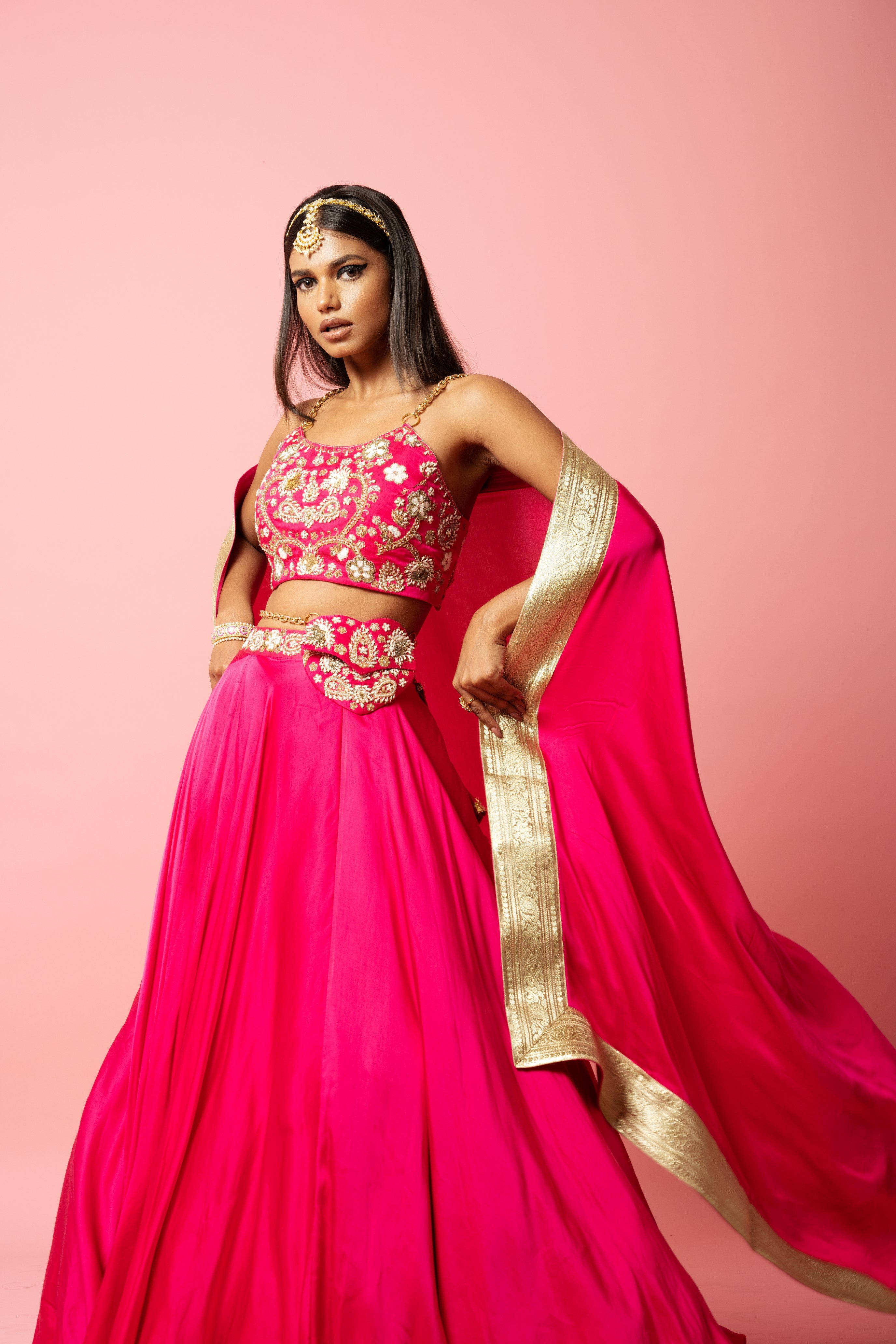 Hot pink lehenga with hand embroidery, lace dupatta, and metal sleeves.