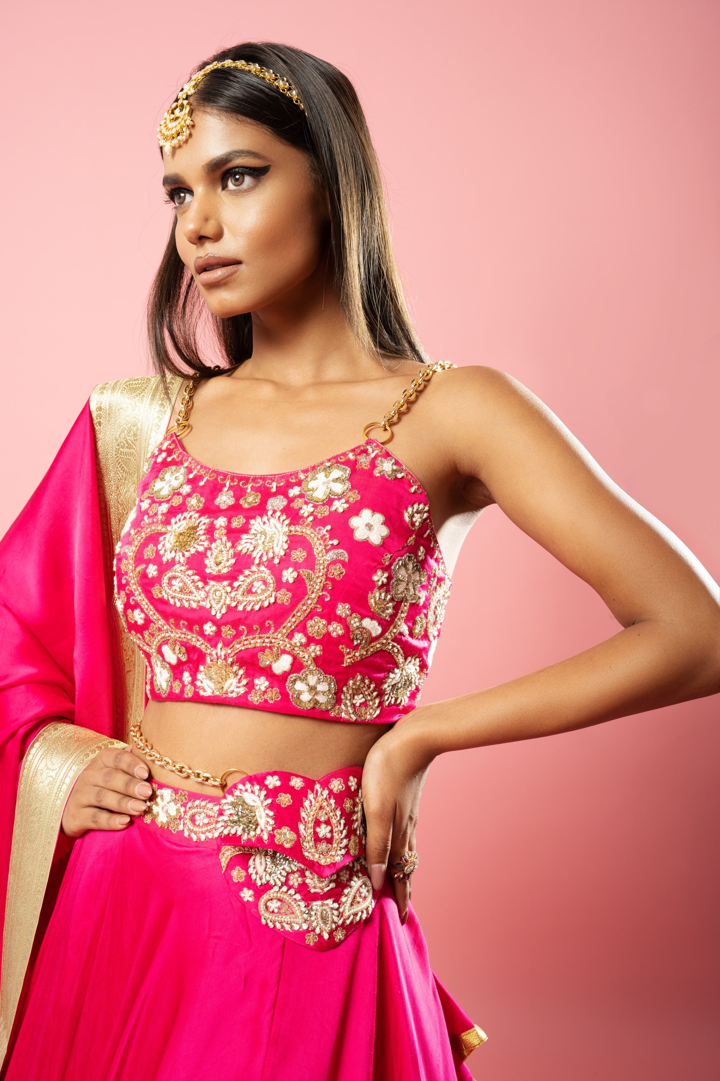 Hot pink lehenga with hand embroidery, lace dupatta, and metal sleeves.