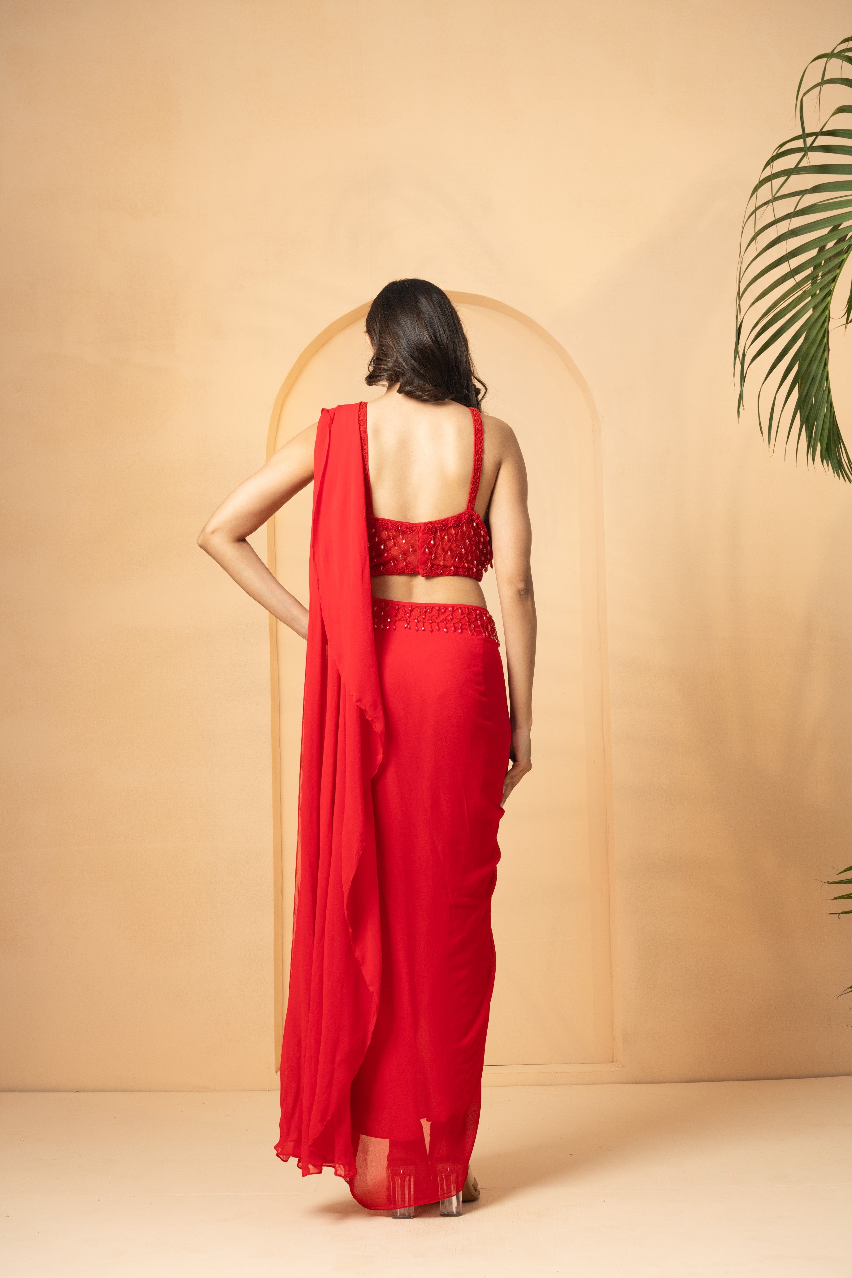 Red pre-stitched drape saree with a corset blouse and crystal bead embroidery.