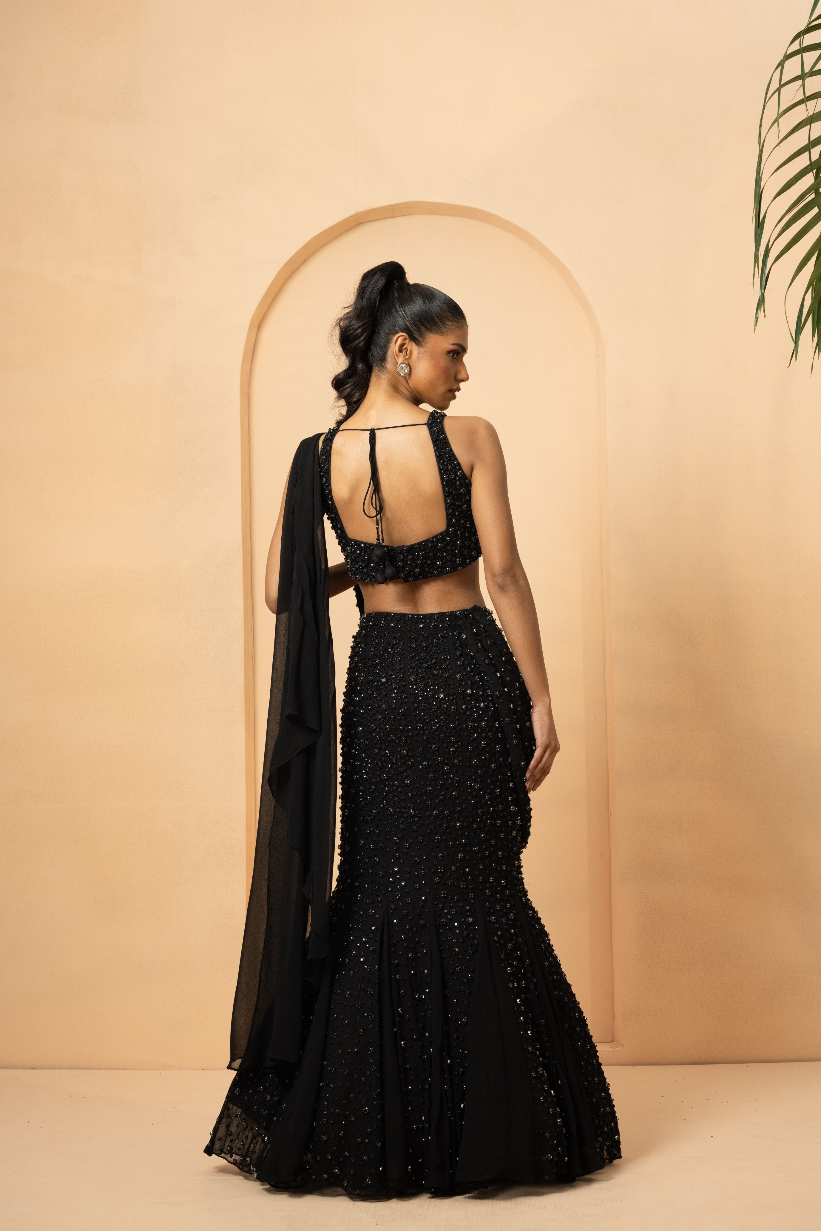 Black fishtail lehenga with twisted drape dupatta and crystal-stone embroidery.