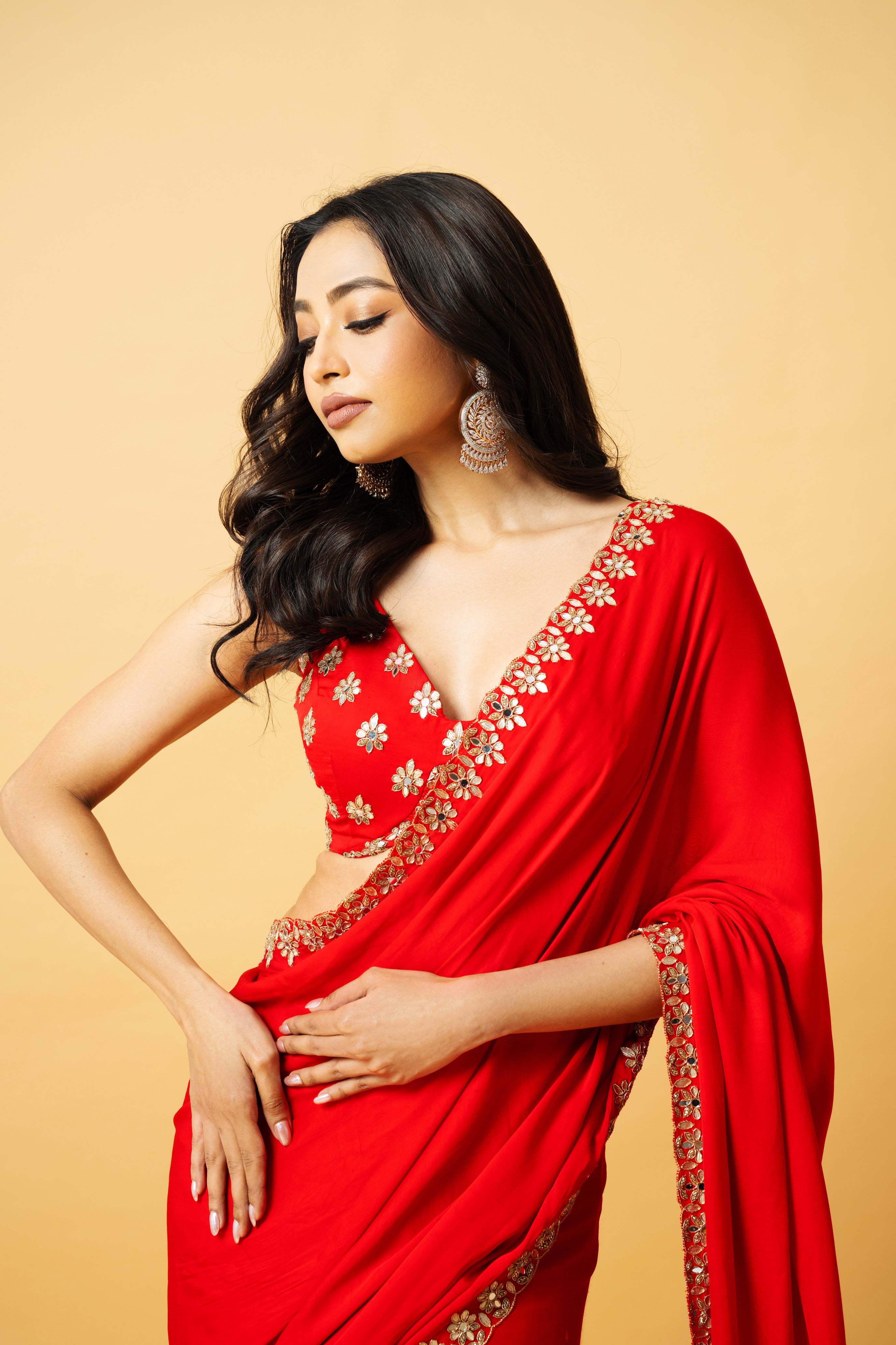 Red modal satin saree with a sleeveless hand-embroidered blouse and pre-draped style.