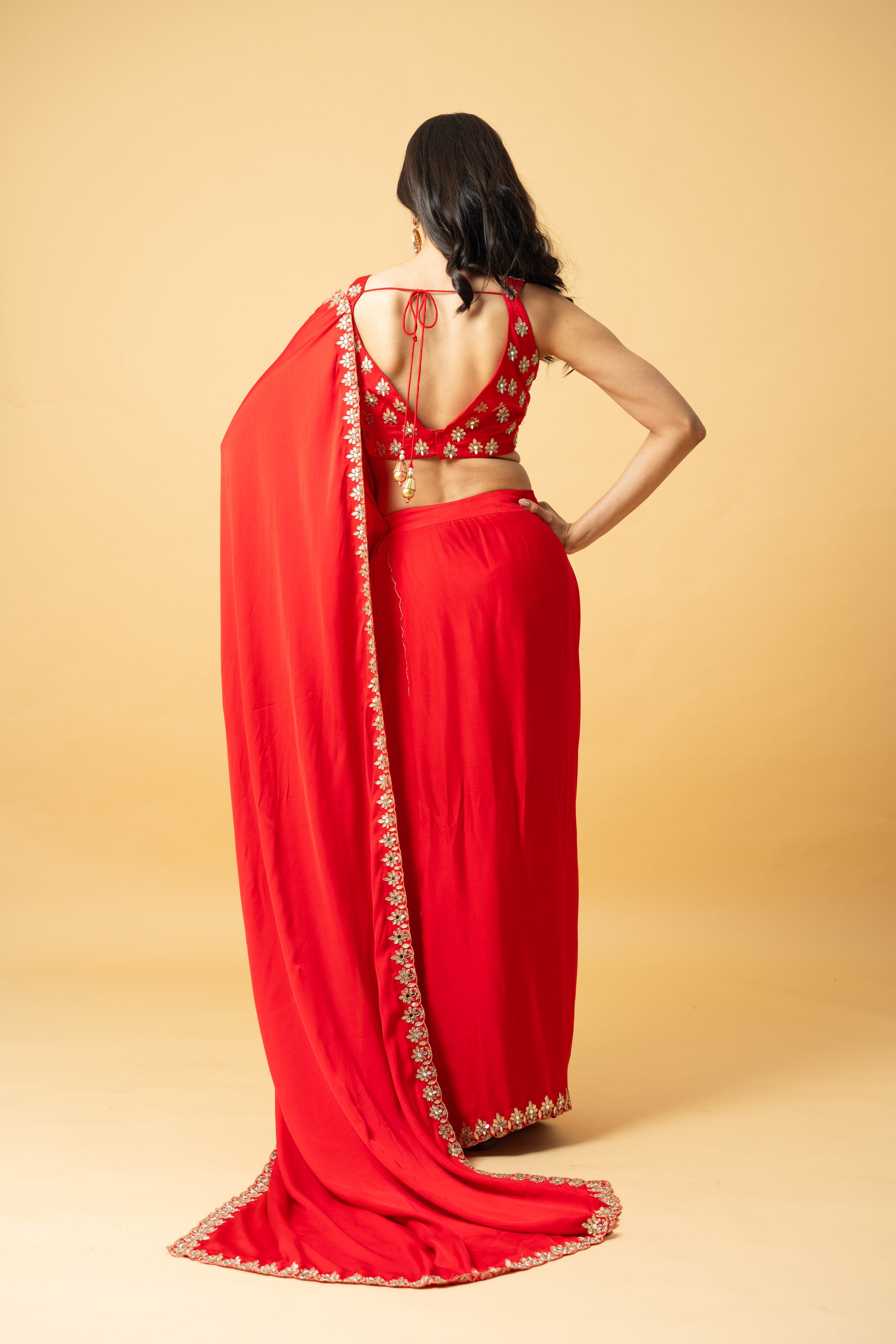 Red modal satin saree with a sleeveless hand-embroidered blouse and pre-draped style.