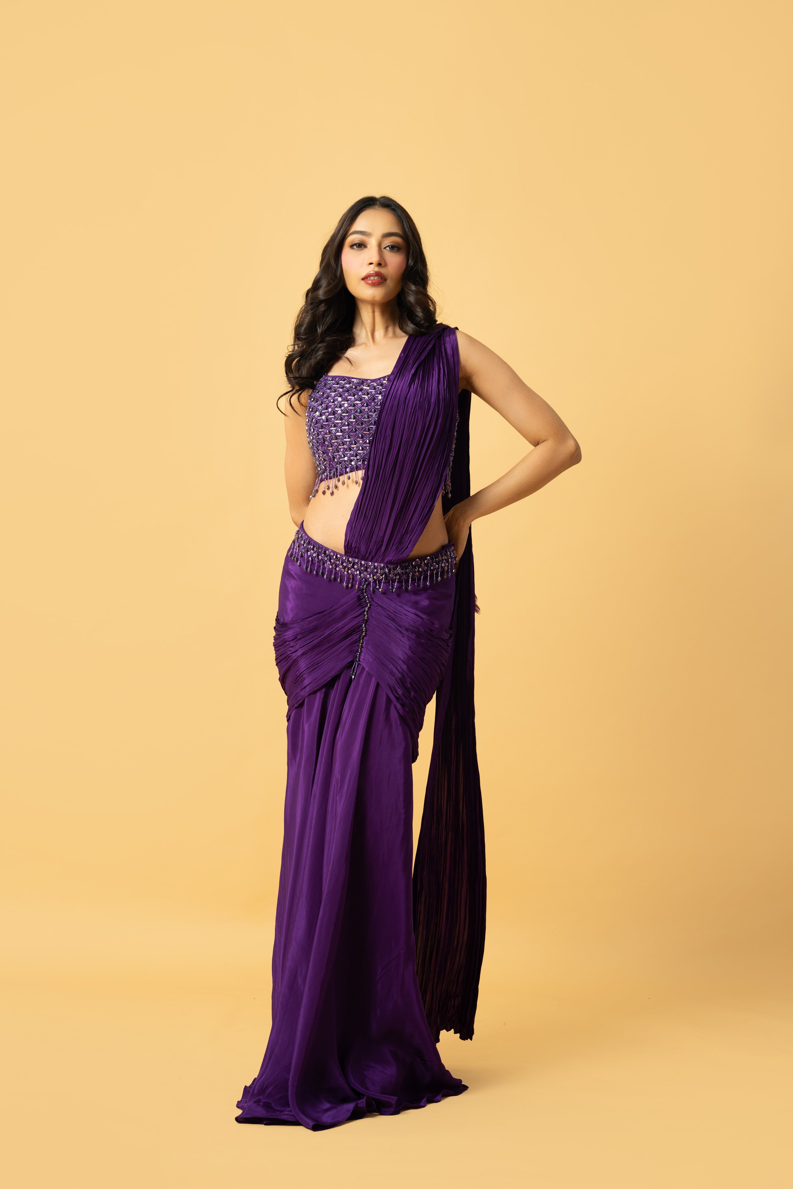 Violet crepe saree with hand-embroidered sleeveless blouse and pre-draped design.