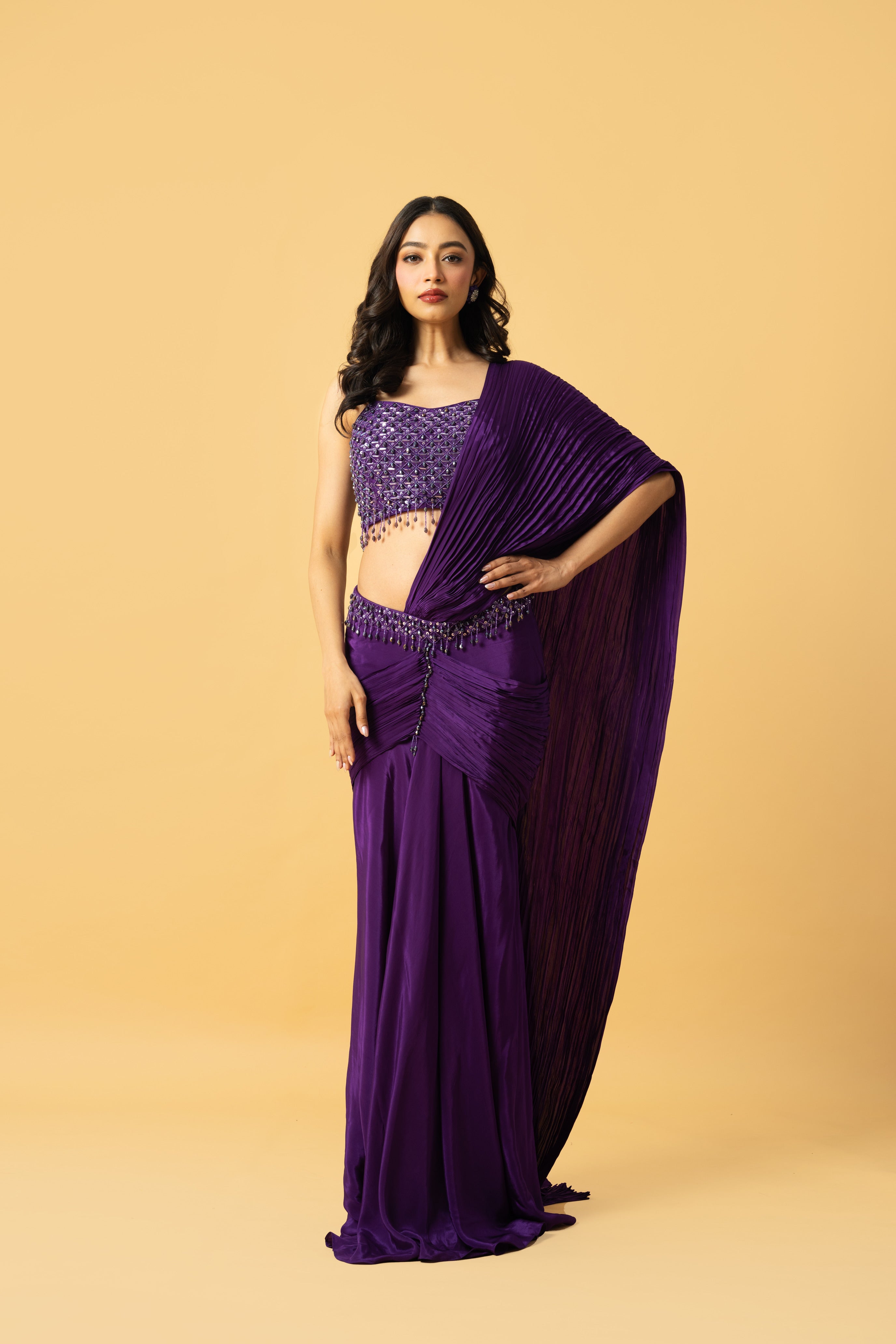 Violet crepe saree with hand-embroidered sleeveless blouse and pre-draped design.