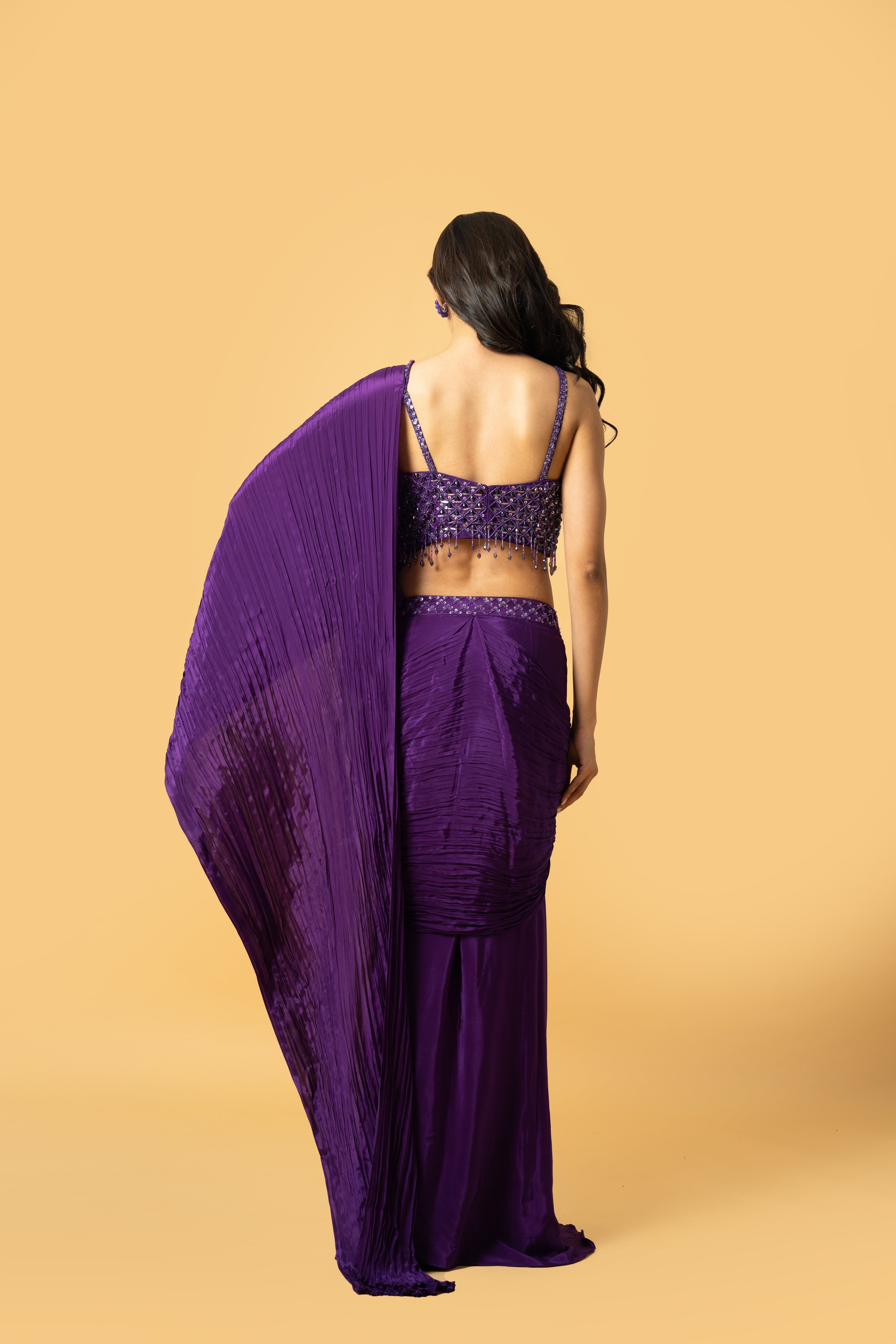 Violet crepe saree with hand-embroidered sleeveless blouse and pre-draped design.