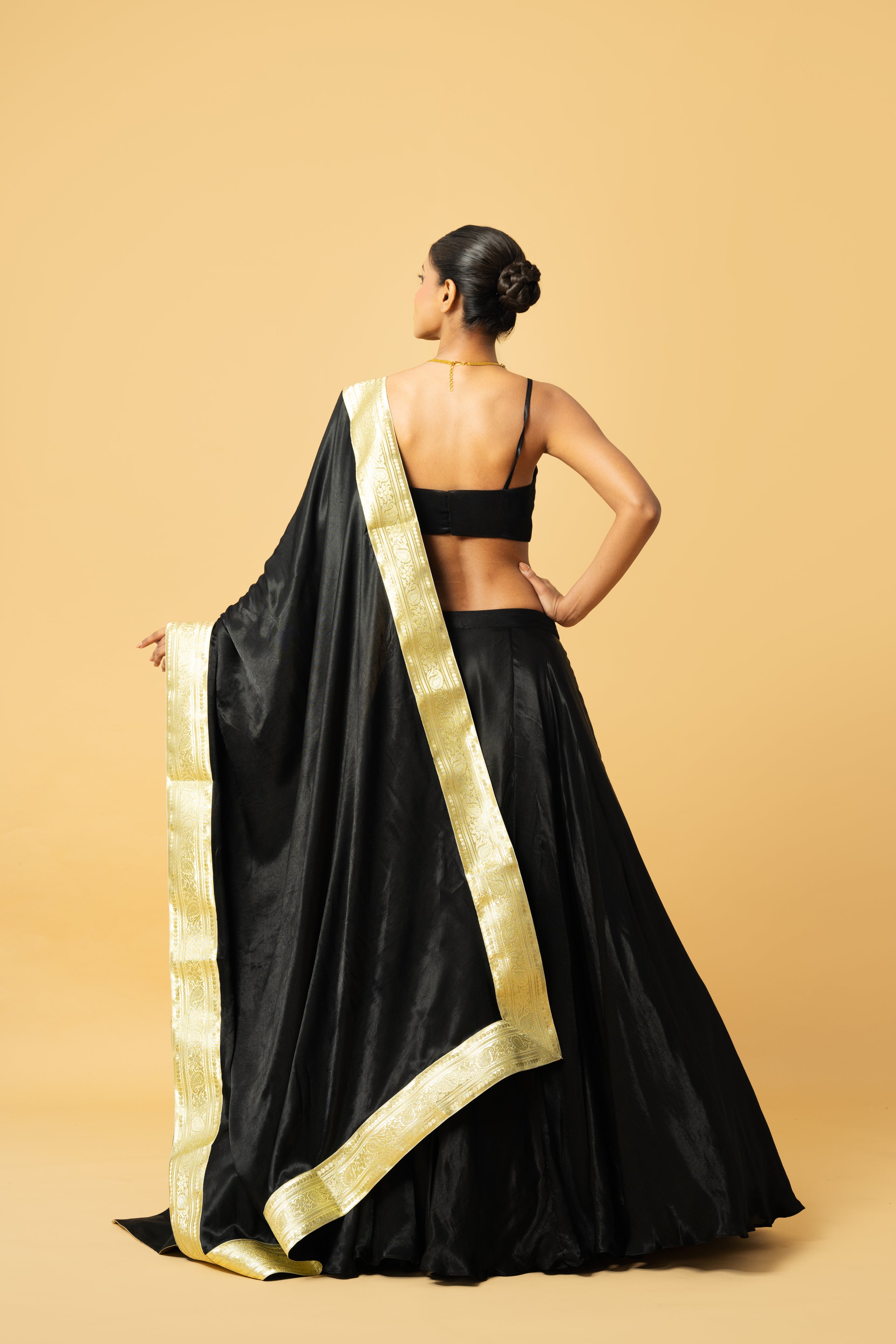 Black modal satin lehenga with sleeveless blouse and golden lace dupatta.