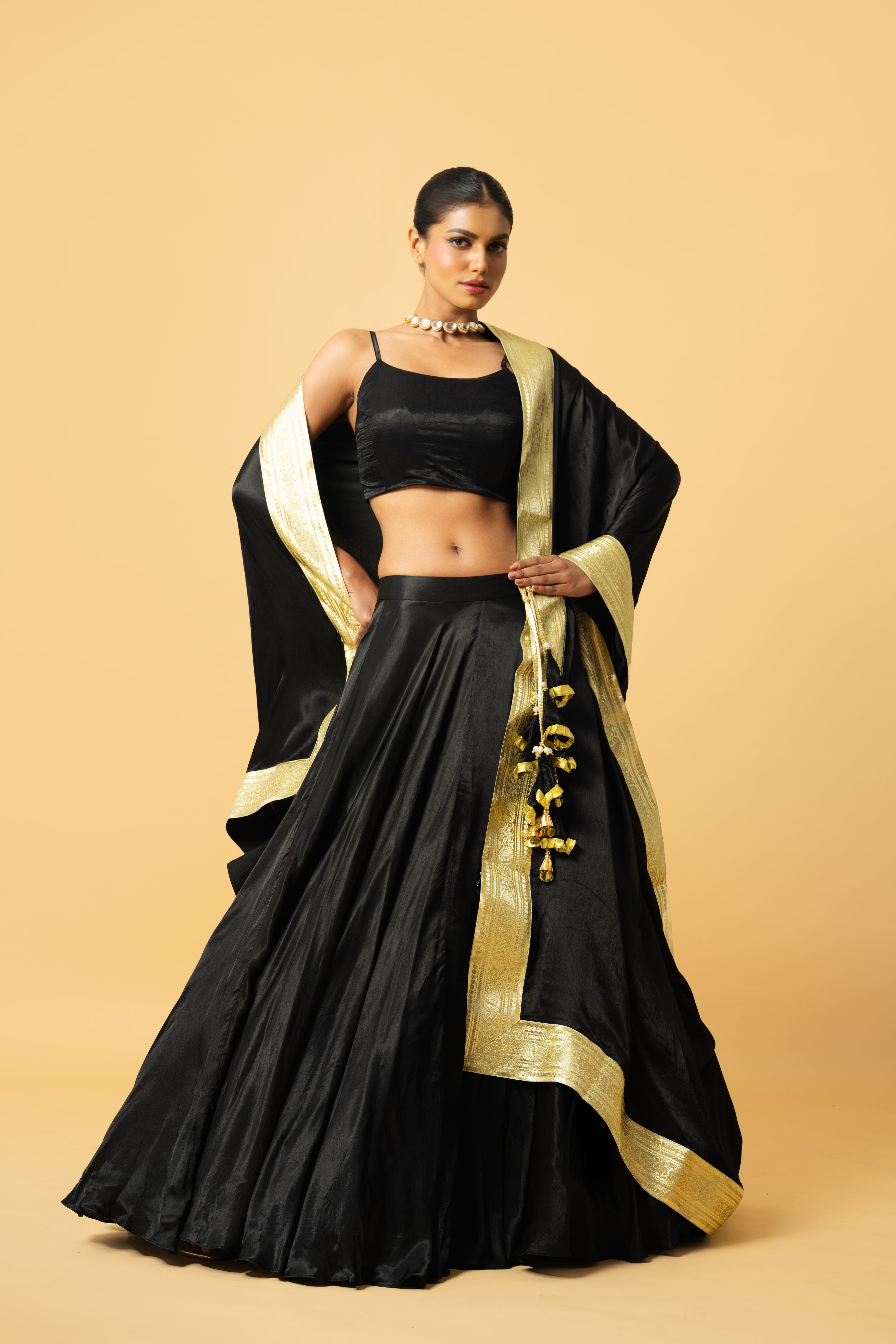Black modal satin lehenga with sleeveless blouse and golden lace dupatta.