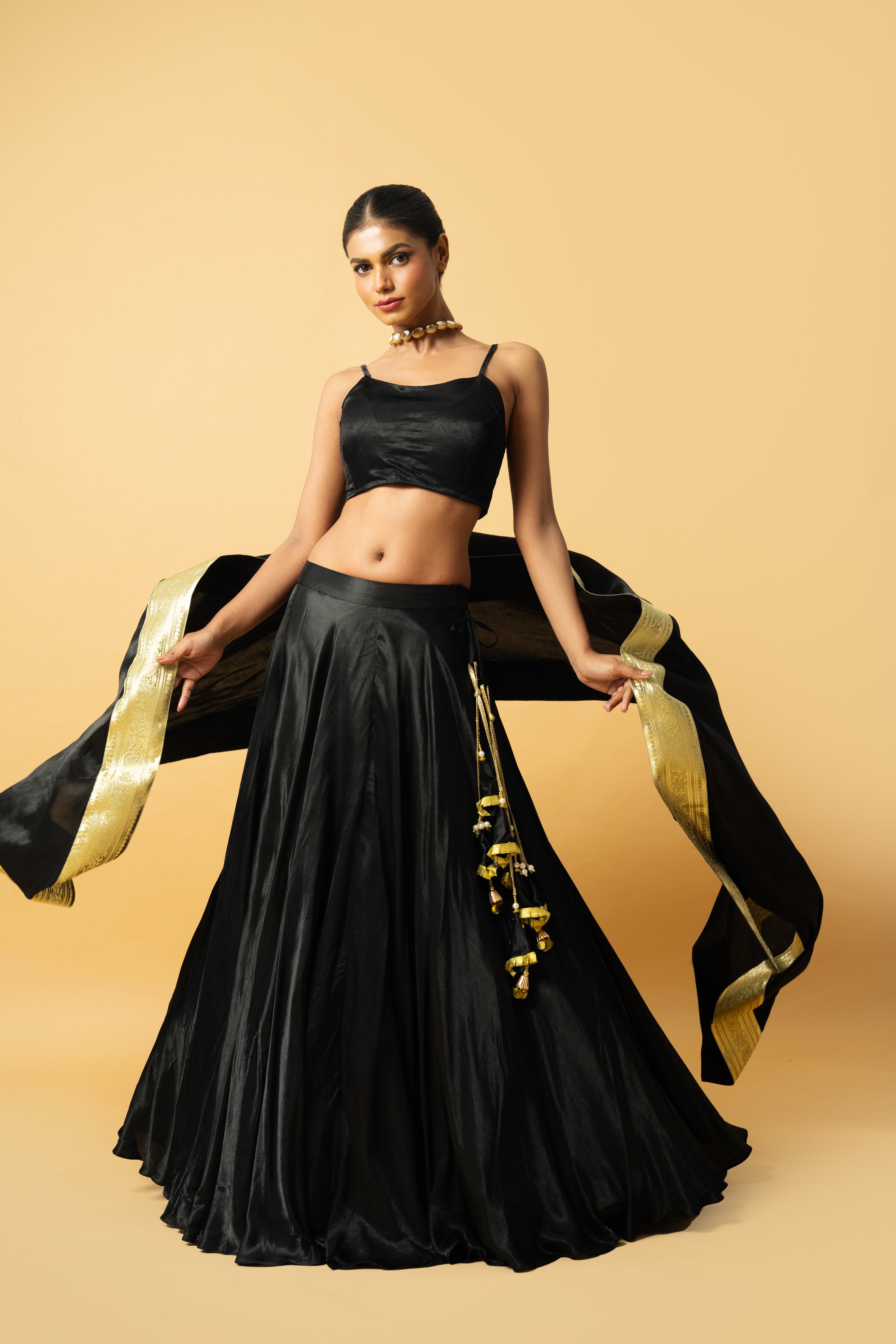 Black modal satin lehenga with sleeveless blouse and golden lace dupatta.