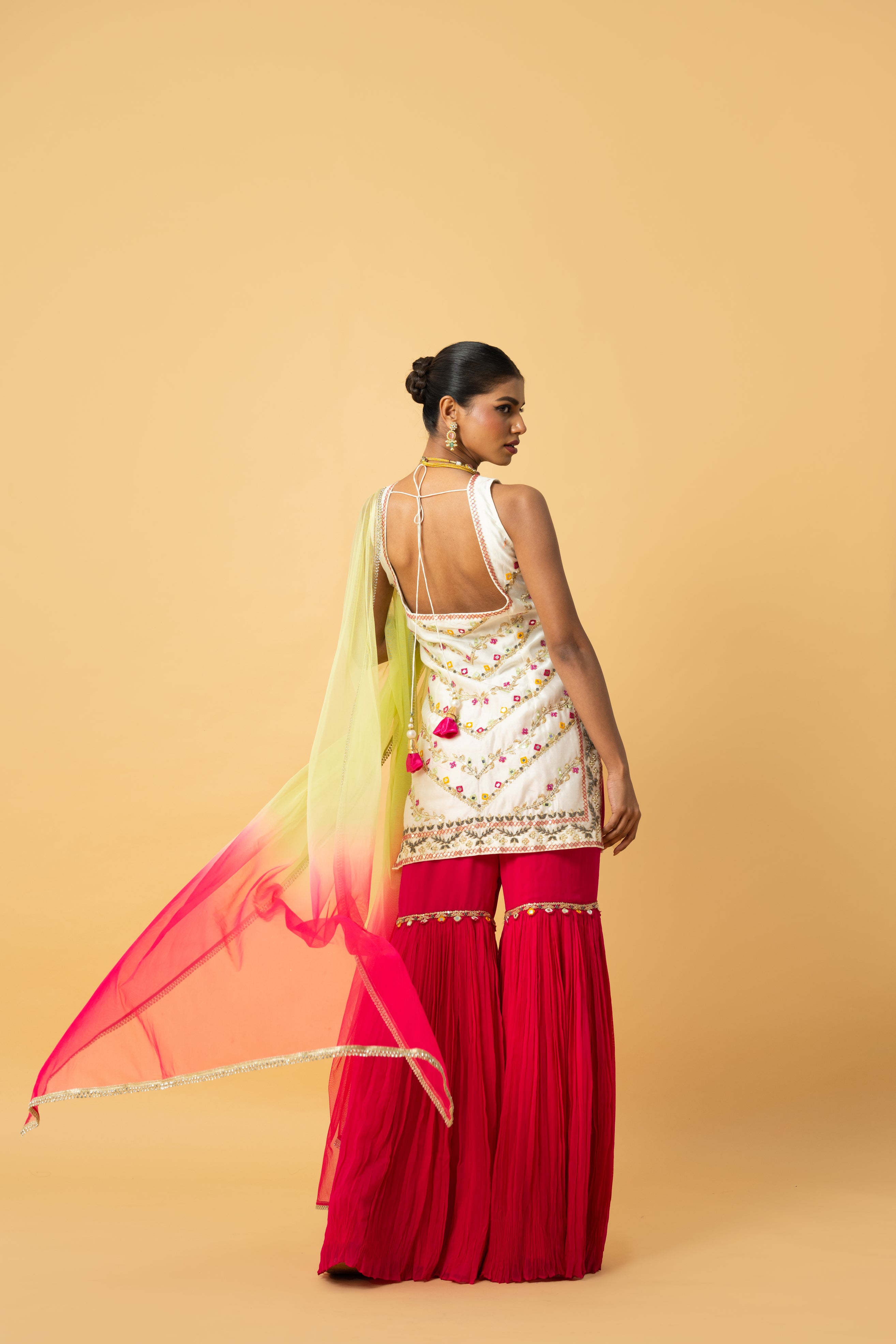 Ivory kurta with pink sharara and lime green dupatta featuring hand embroidery.