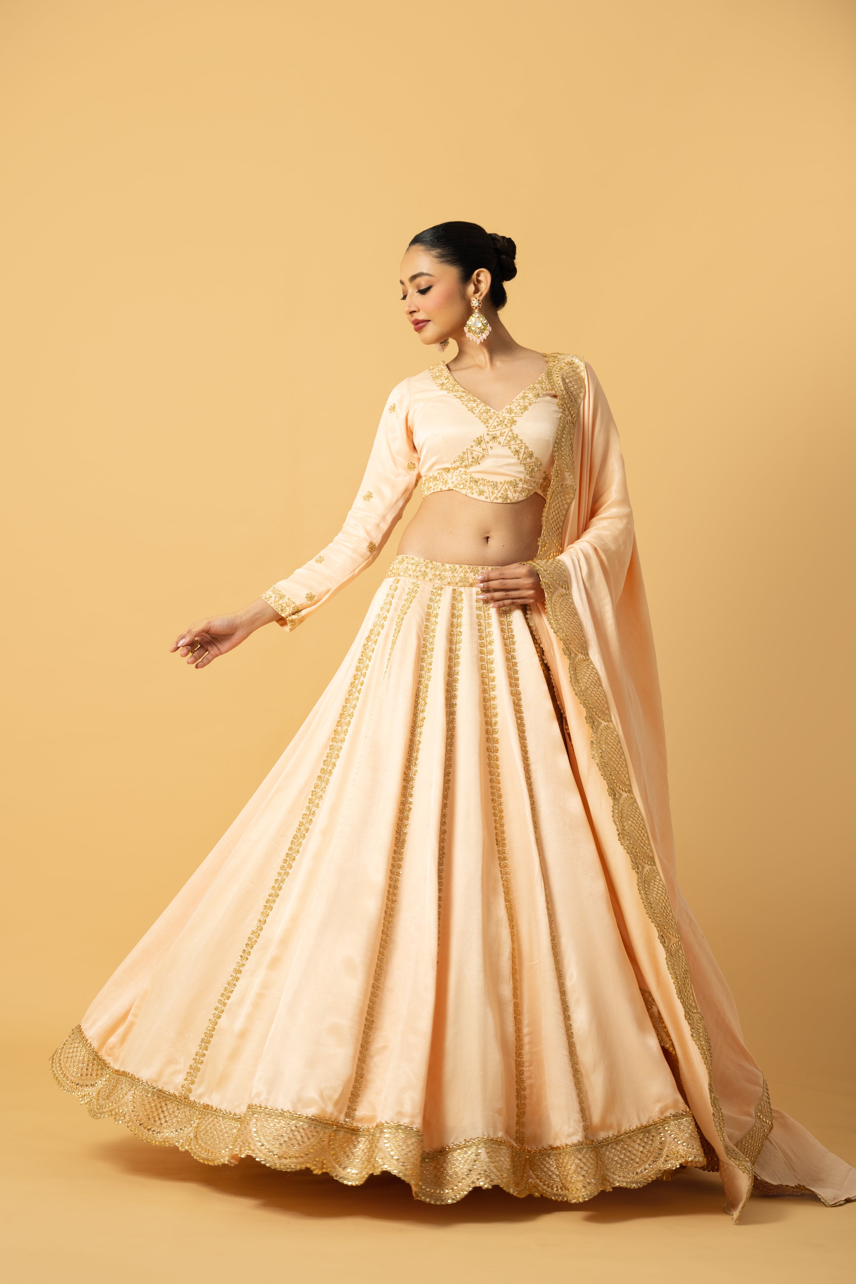 Peach modal satin lehenga with full sleeves, hand embroidery, and lace-trimmed dupatta.