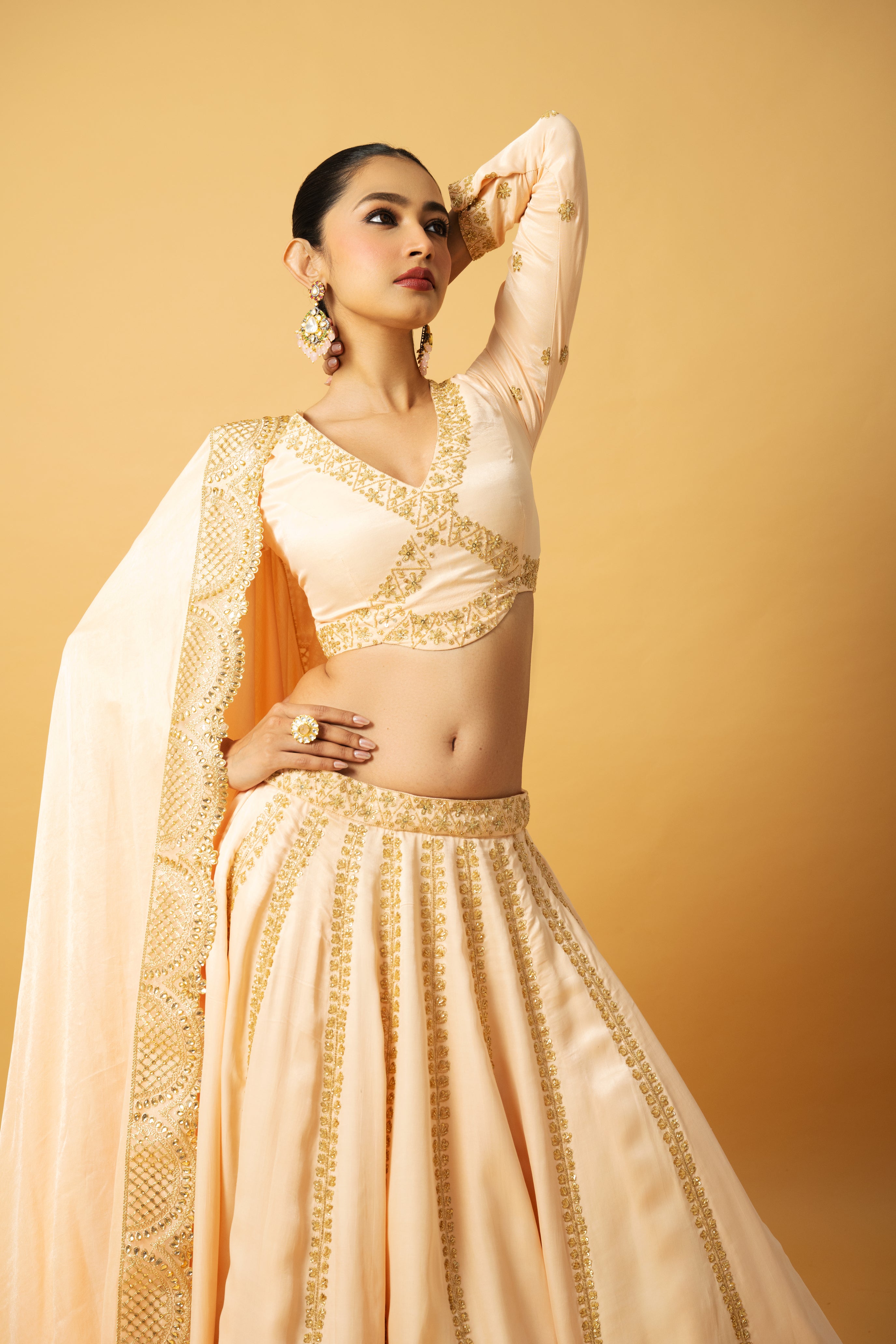 Peach modal satin lehenga with full sleeves, hand embroidery, and lace-trimmed dupatta.