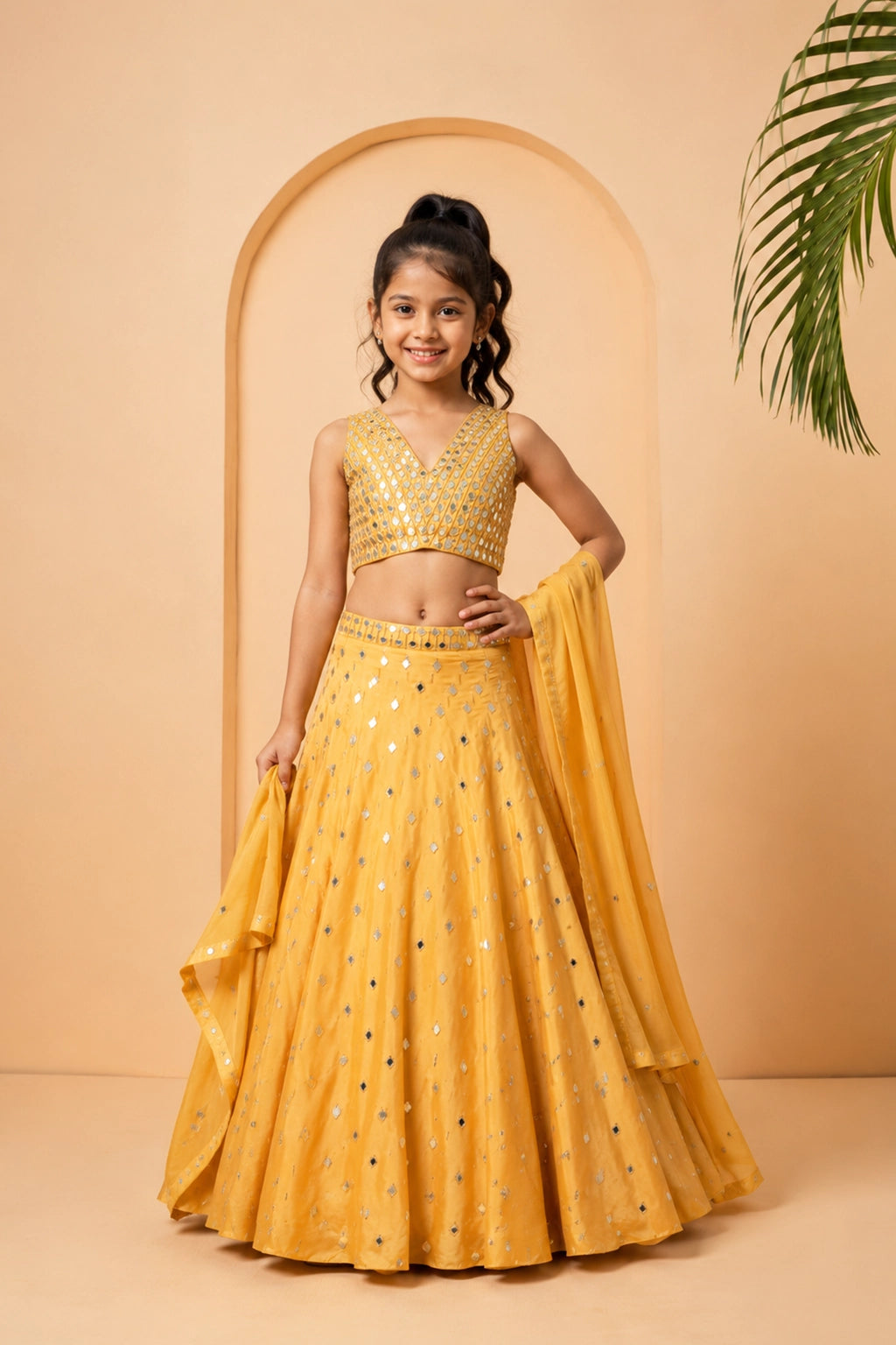 Golden lehenga in modal satin with intricate mirror work and pearl bead details.