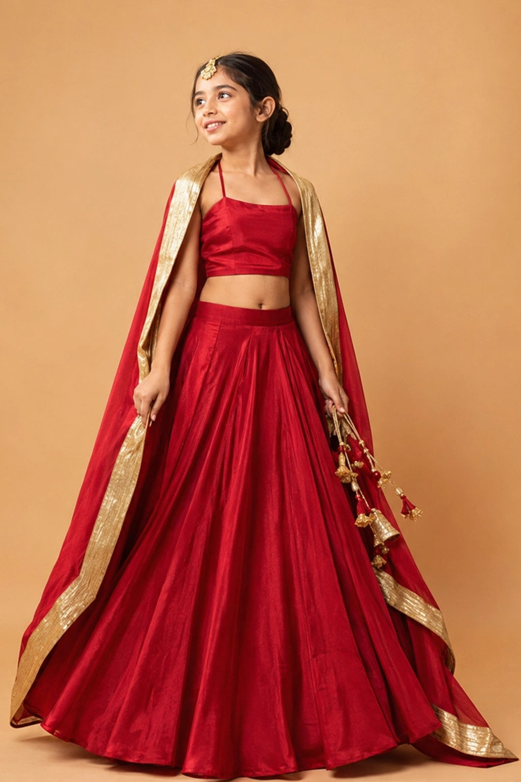 A bold deep red lehenga in modal fabric with a sleeveless blouse. The dupatta has a golden zari along the border for a rich, traditional finish