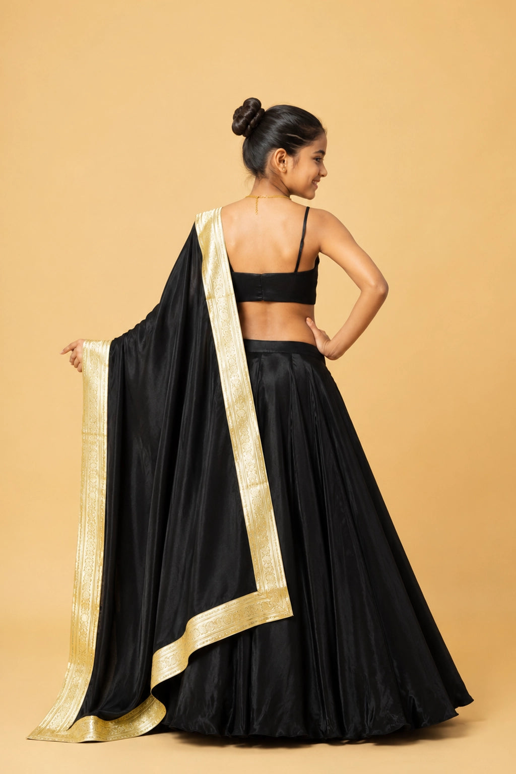 A black modal satin lehenga paired with a sleeveless blouse and a dupatta adorned with golden lace and latkan details.