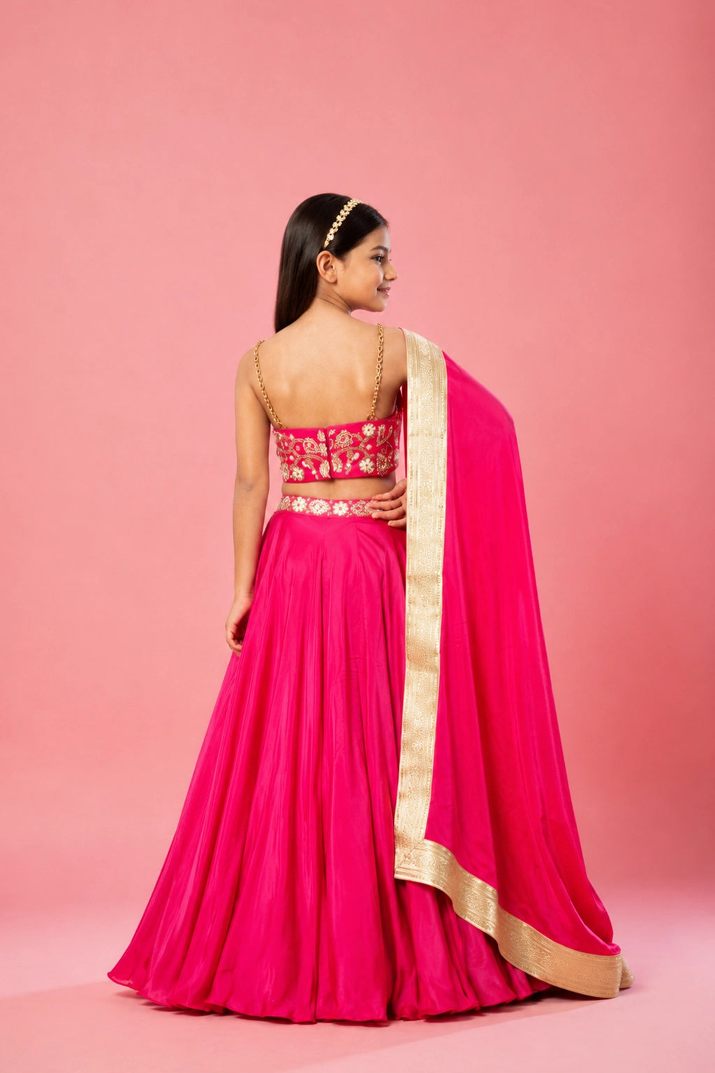 Hot pink lehenga set in modal satin with metal sleeves and a hand-embroidered heart-shaped pouch and belt. The dupatta is adorned with lace detailing for an extra touch of elegance.
