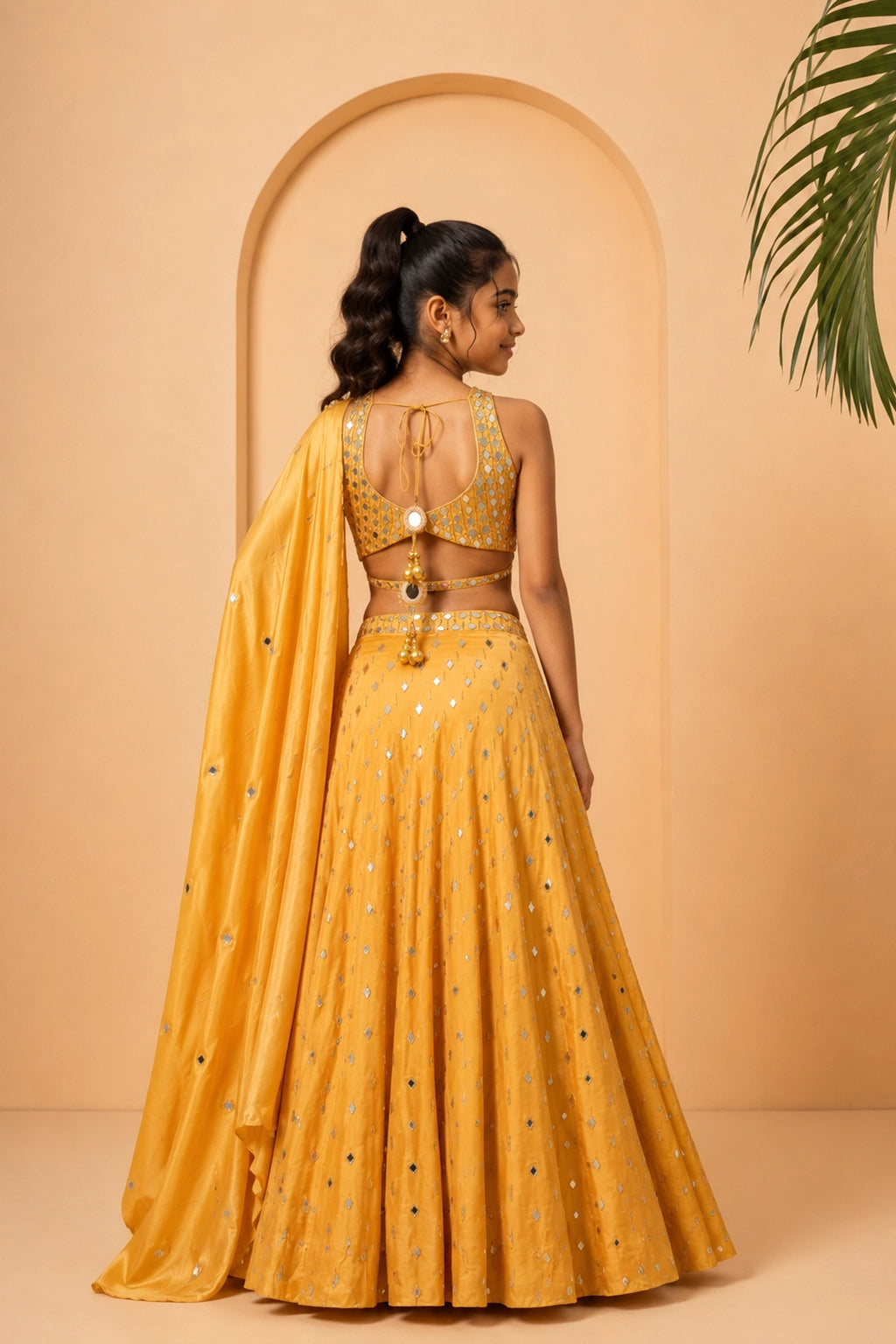 Golden lehenga in modal satin with intricate mirror work and pearl bead details.