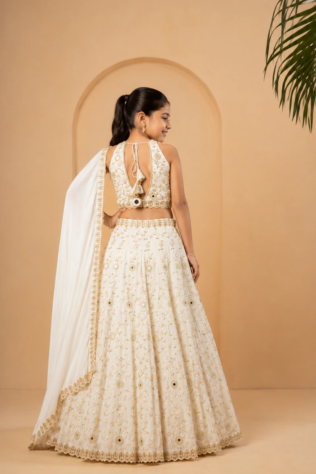 Ivory lehenga made from modal satin fabric, adorned with intricate mirror and pearl bead embellishments across the lehenga, blouse, and dupatta.