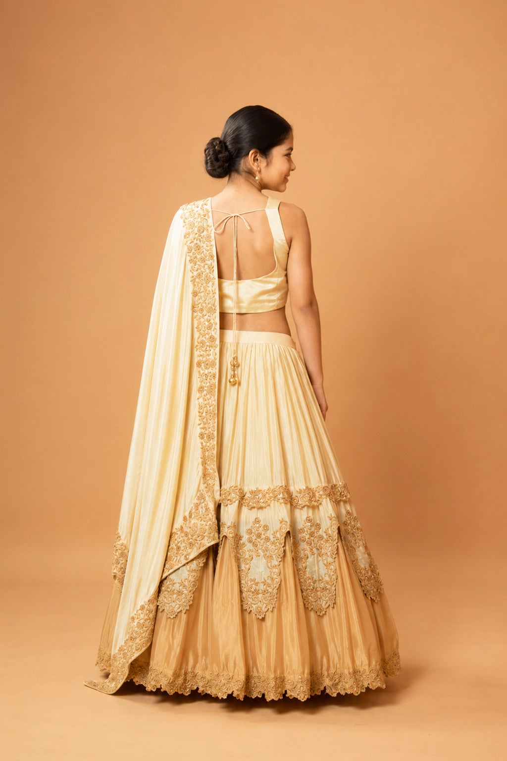 A layered golden ombre lehenga with intricate floral motifs crafted using kardana and zari threadwork.