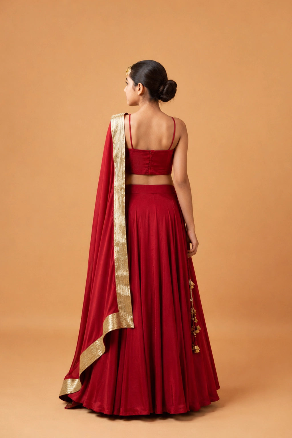 A bold deep red lehenga in modal fabric with a sleeveless blouse. The dupatta has a golden zari along the border for a rich, traditional finish