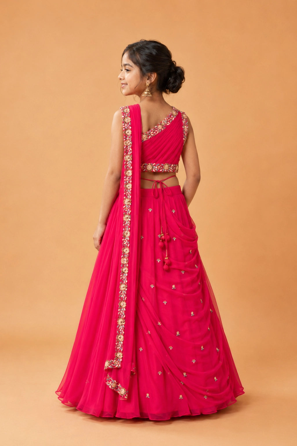 Fuchsia pink draped lehenga in georgette is paired with a matching hand-embroidered waist belt.