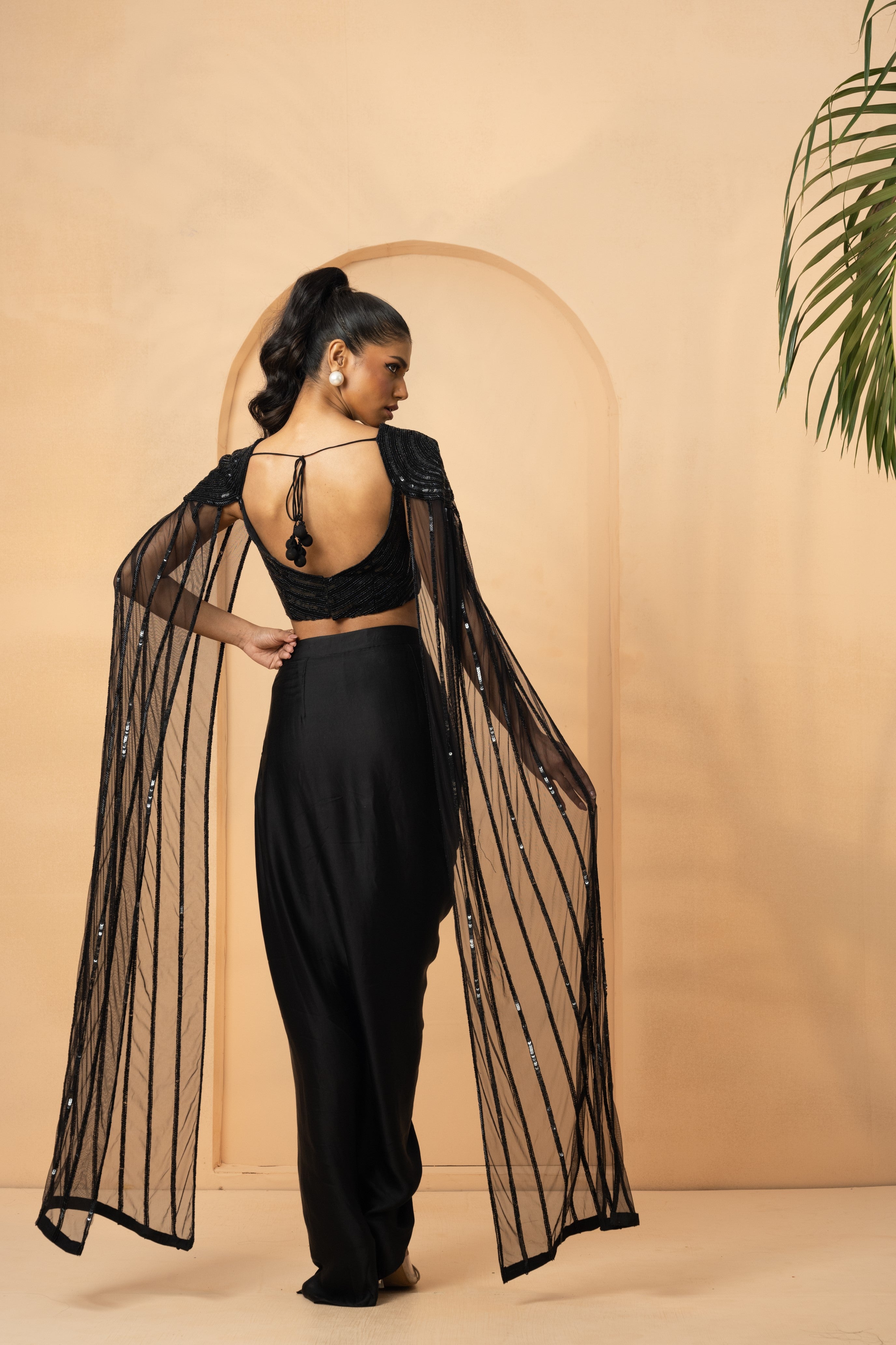 Black dhoti co-ord set with hand-embroidered blouse and attached cape.