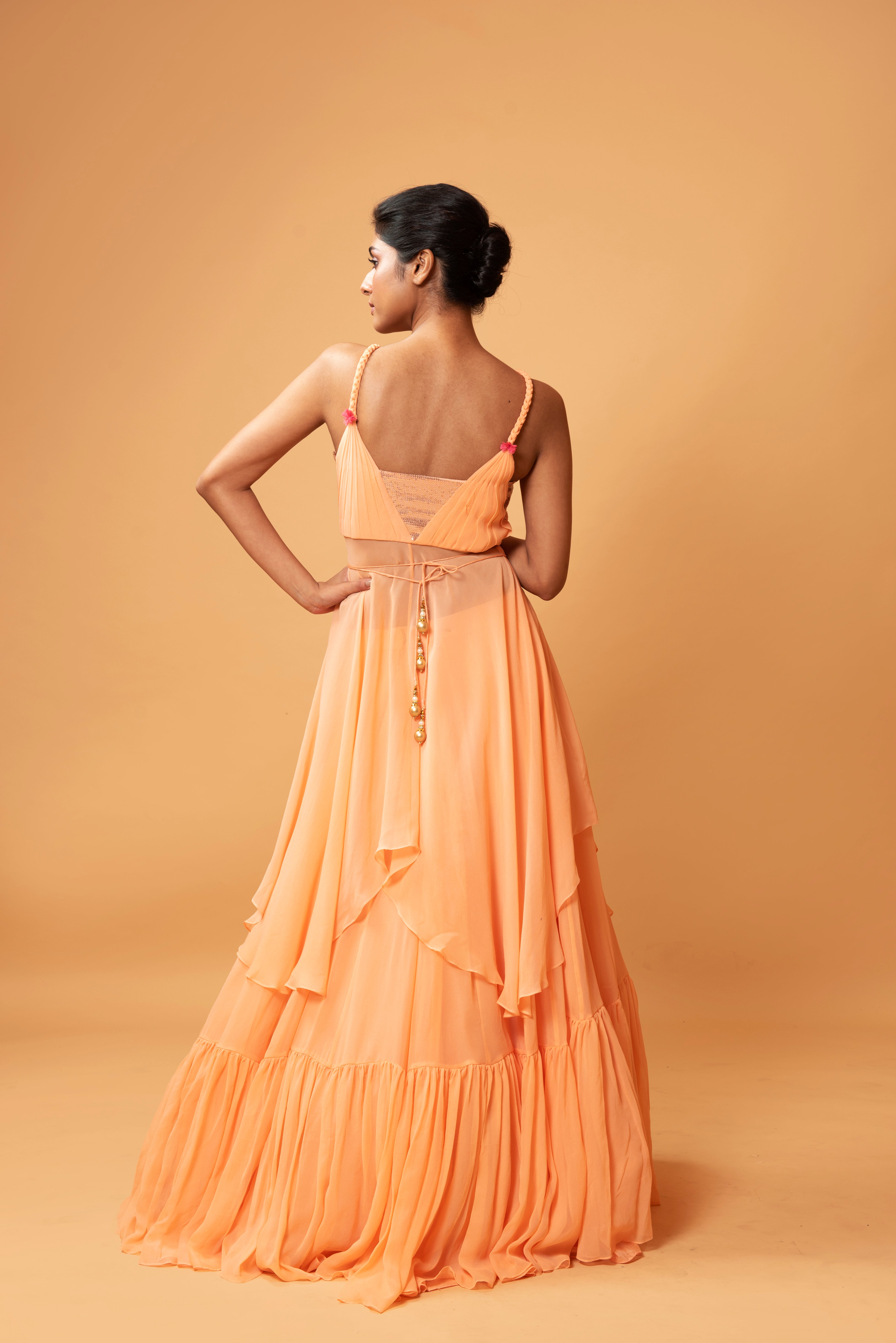 Peach sleeveless co-ord set with sequins, ruffled lehenga, and mirror-embellished waist belt.
