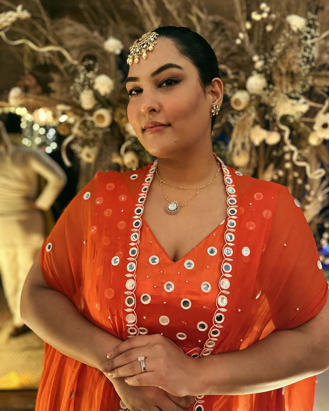 Sakshi Sindhwani wearing a tangerine orange dhoti set with mirror work blouse and cape.